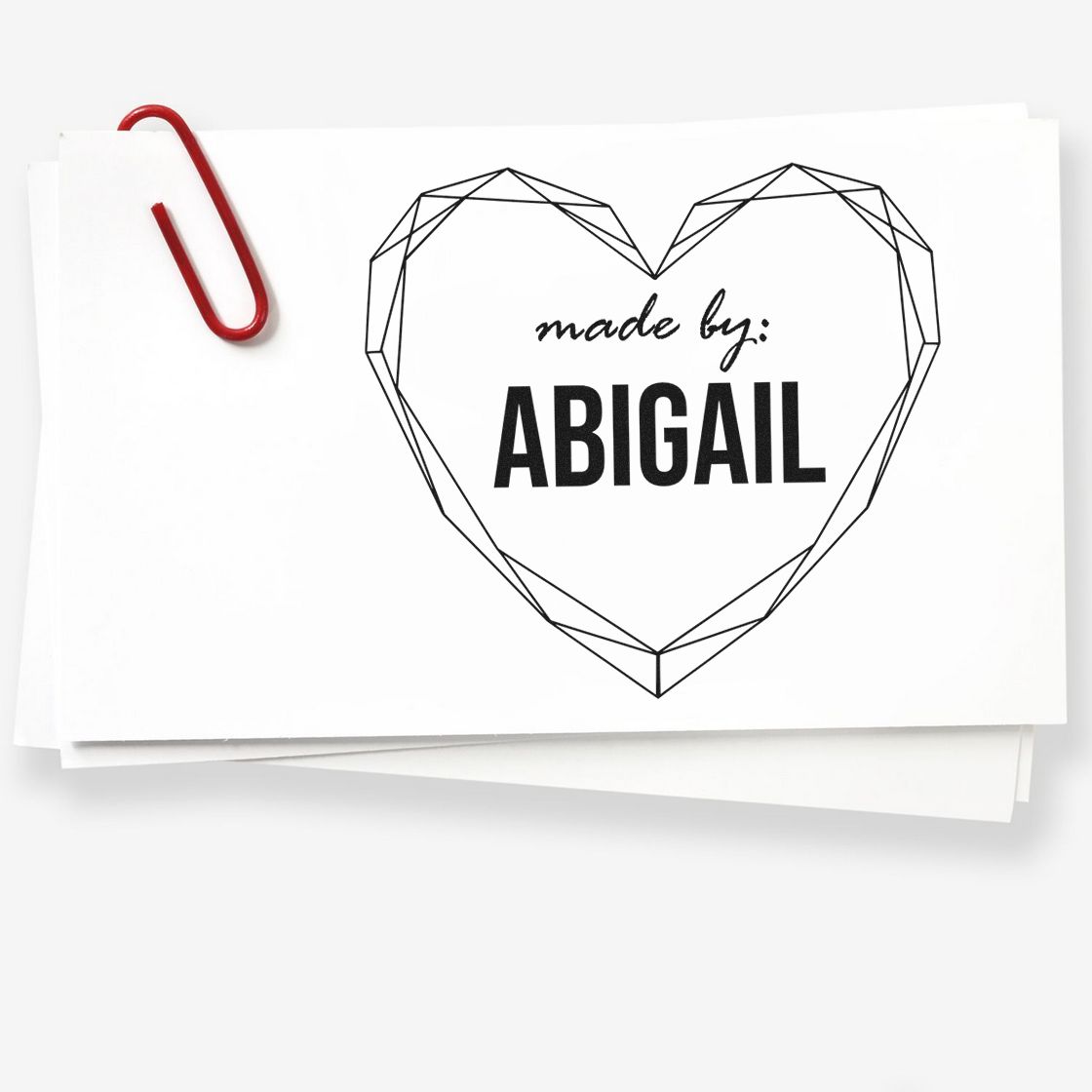 Custom heart seal stamp reading made by: ABIGAIL on white cards, accented with a red paperclip.