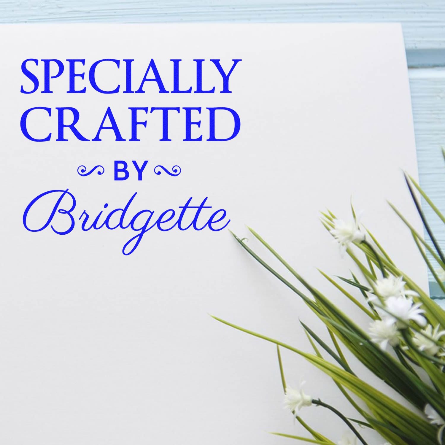 White custom stamp and seal card with bold blue Specially Crafted by Bridgette text and green floral accents.