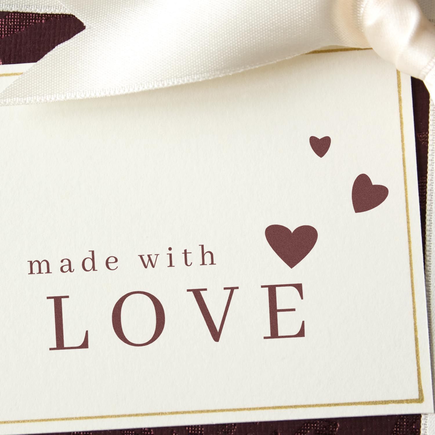 Cream stamp and seal card with burgundy hearts, made with LOVE text, and a thin gold border.