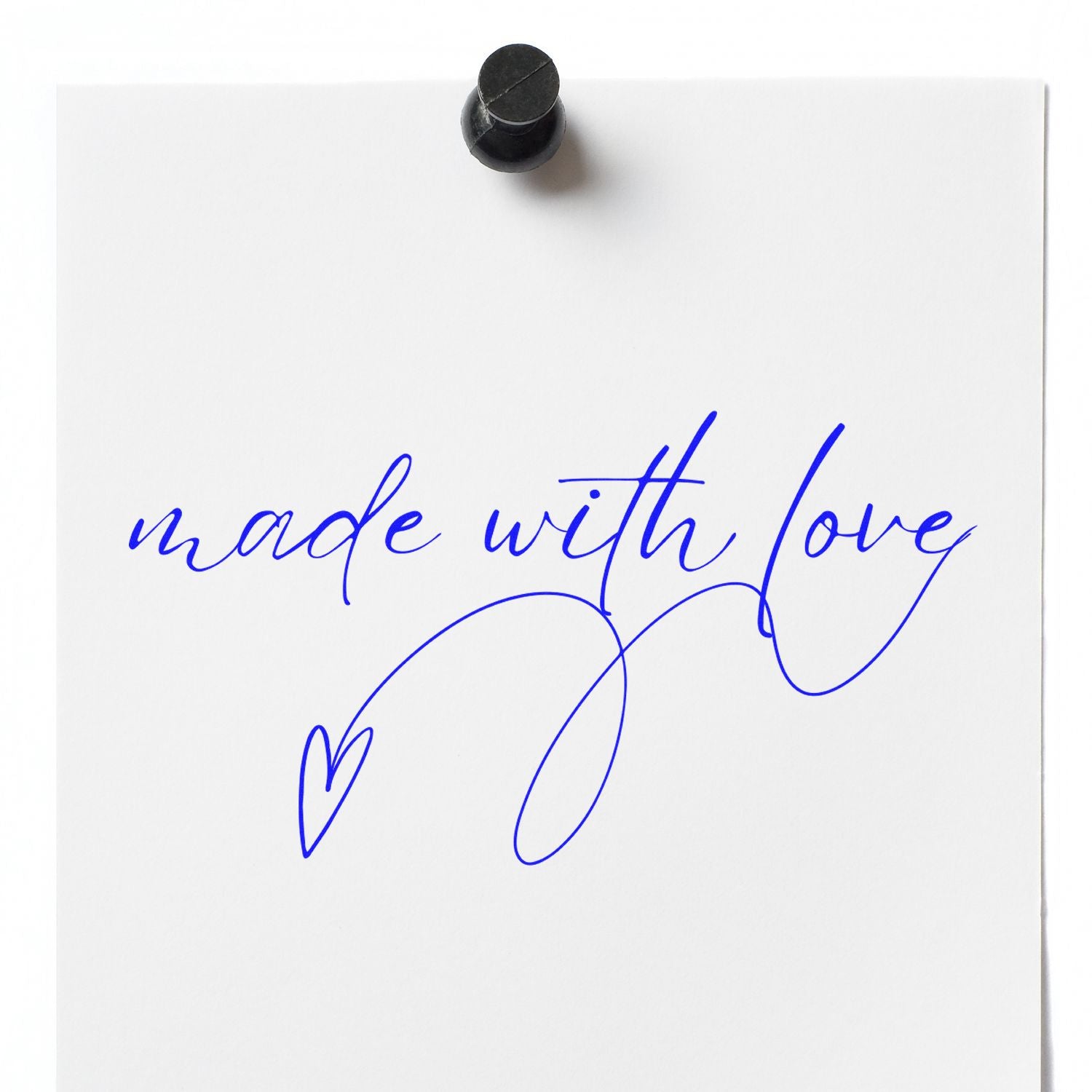 White paper with blue handwritten made with love and heart, pinned by a black stamp seal.