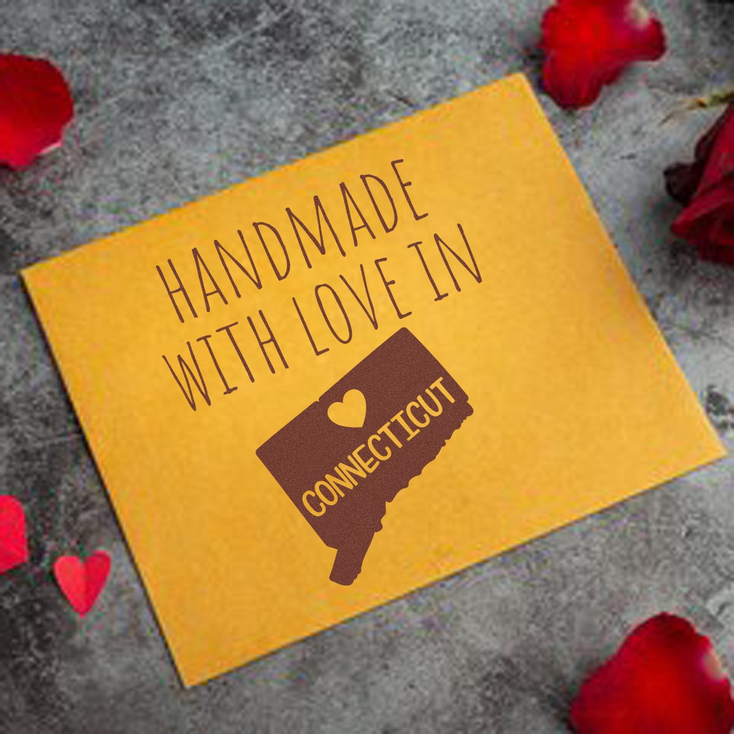 Connecticut handmade rubber stamp with wood handle by ESS, featuring "Made in Connecticut" design in use on paper.