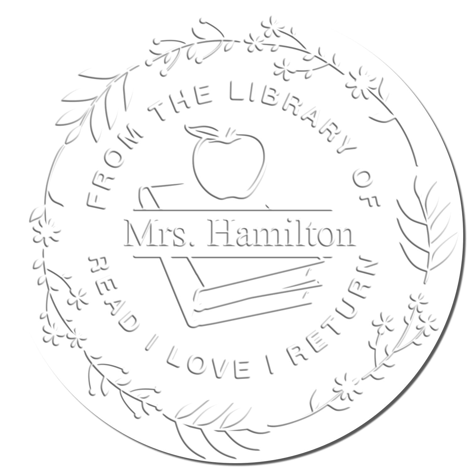 White embossed round library stamp seal with apple, book, floral border and Mrs. Hamilton