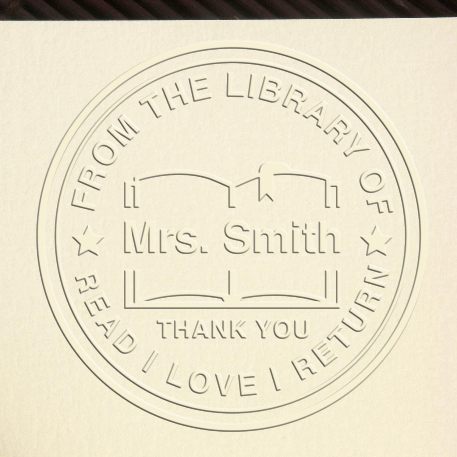 Cream circular embossed library stamp seal with open book icon, stars, and From the Library of Mrs. Smith text.