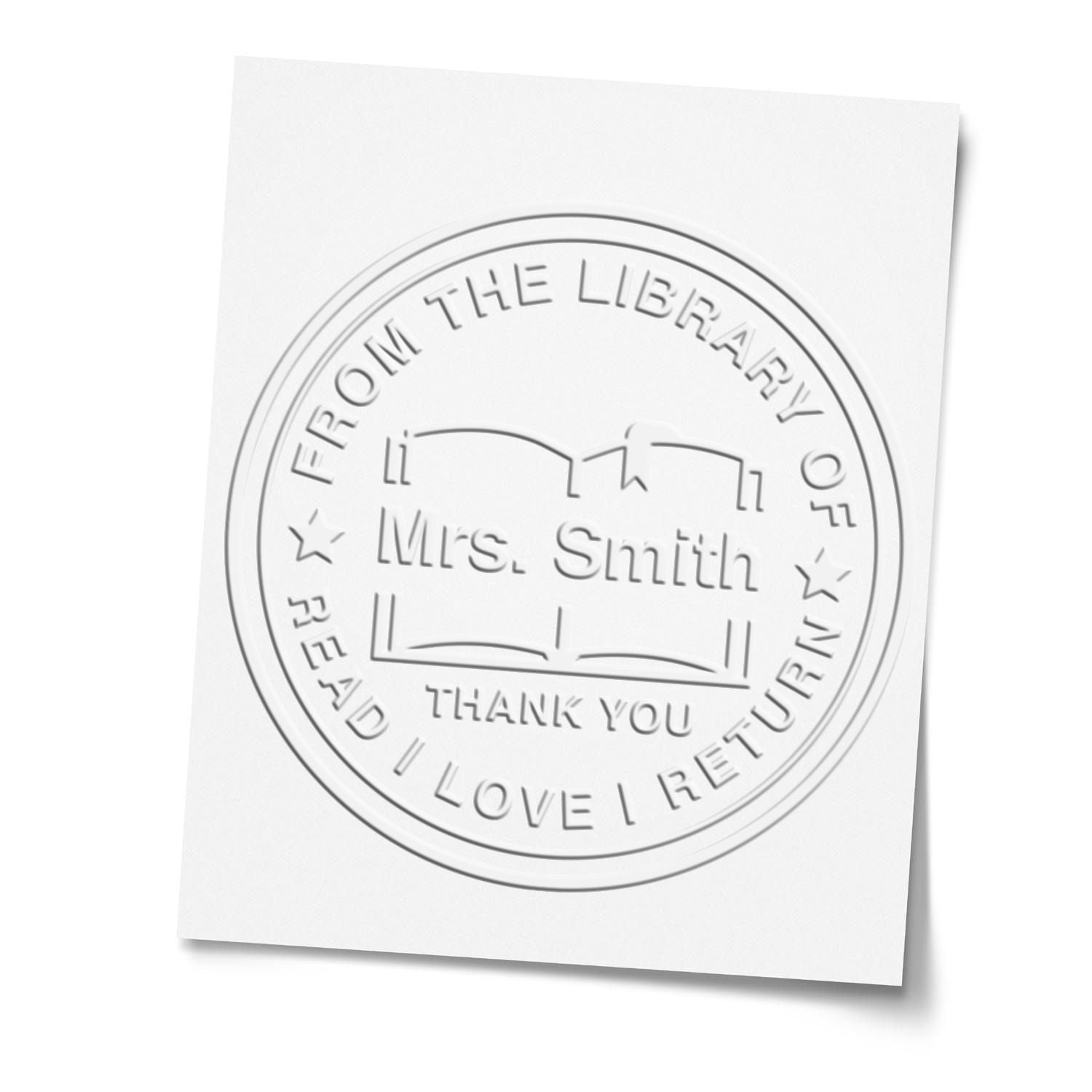 White embossed circular library stamp seal for Mrs. Smith with book icon and thank-you text on white paper.