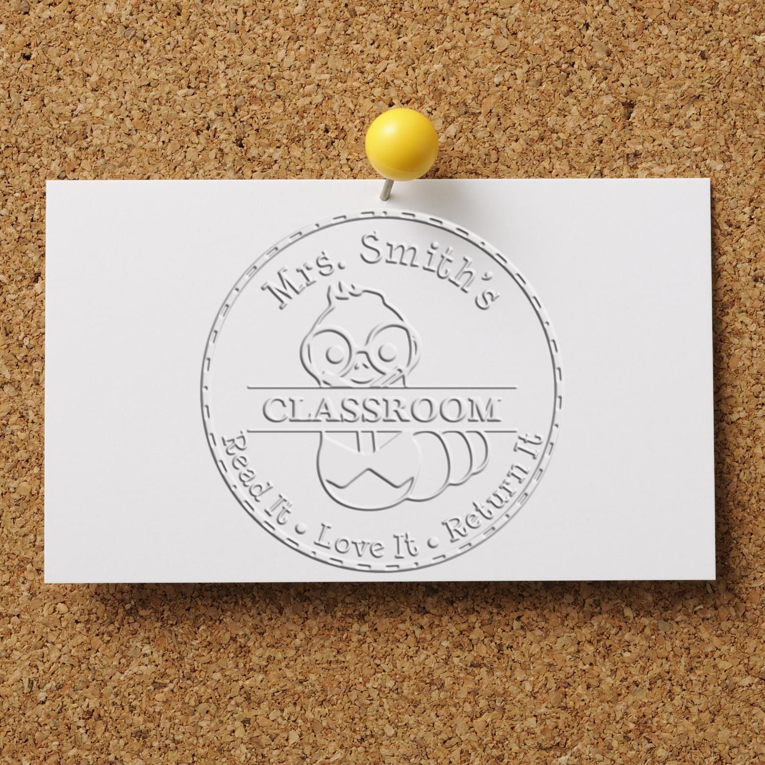 White embossed Mrs. Smiths Classroom stamp seal with owl logo, pinned by a yellow pushpin on corkboard