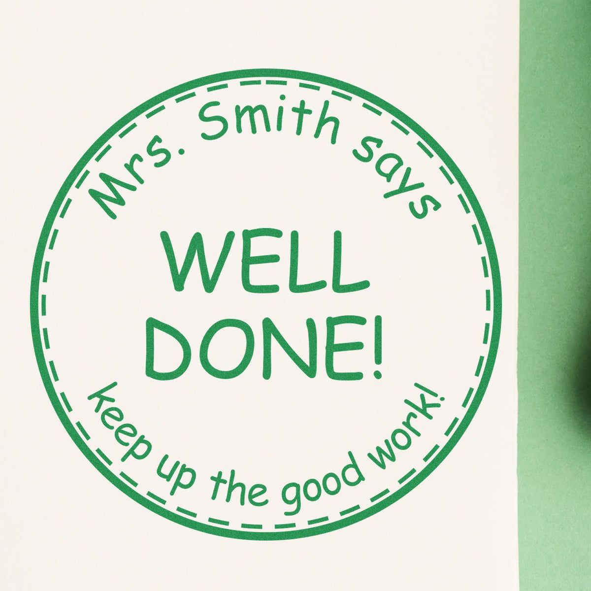 Green circular teacher stamp seal on white paper reading Mrs. Smith says WELL DONE! Keep up the good work!