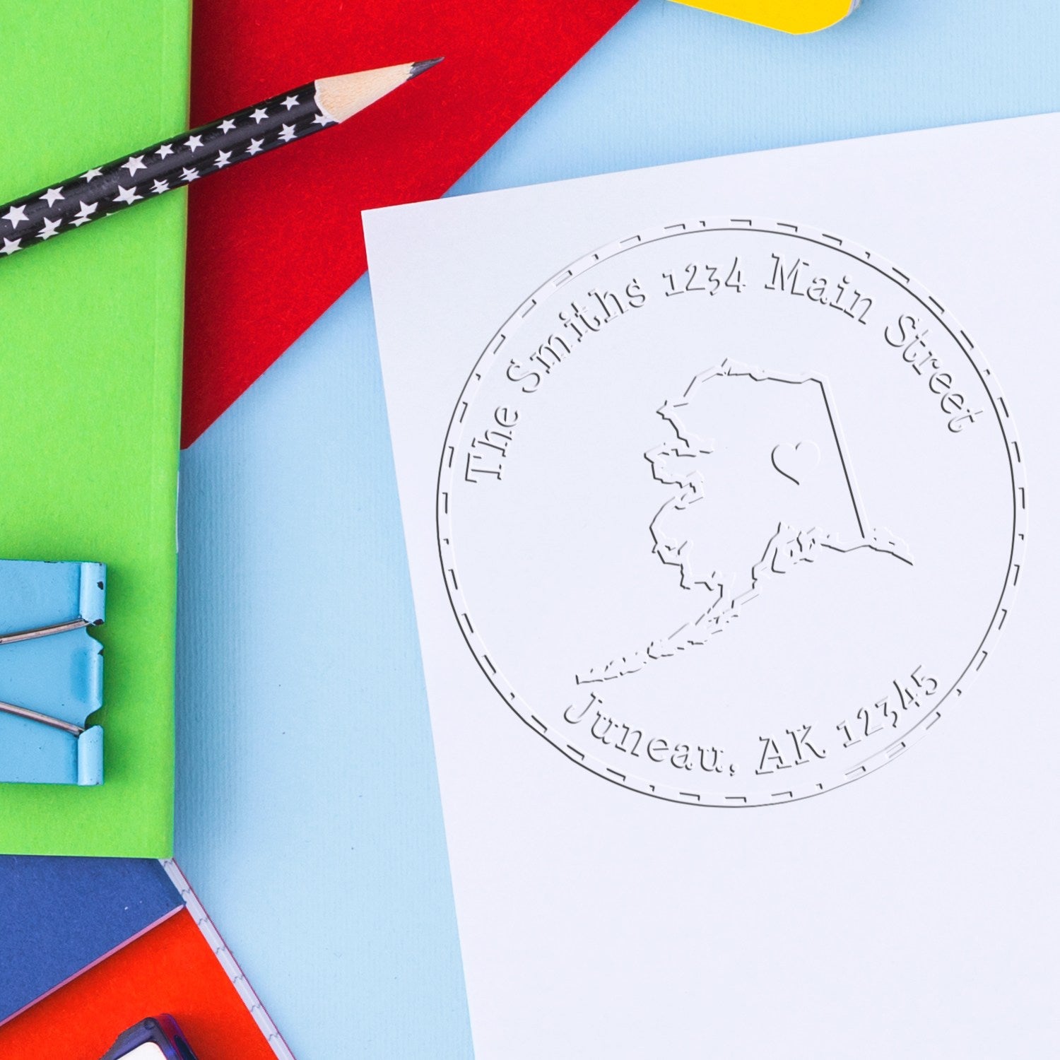 Custom stamp and embossed seal for The Smiths, 1234 Main Street, Juneau, AK, on colorful stationery with star pencil.