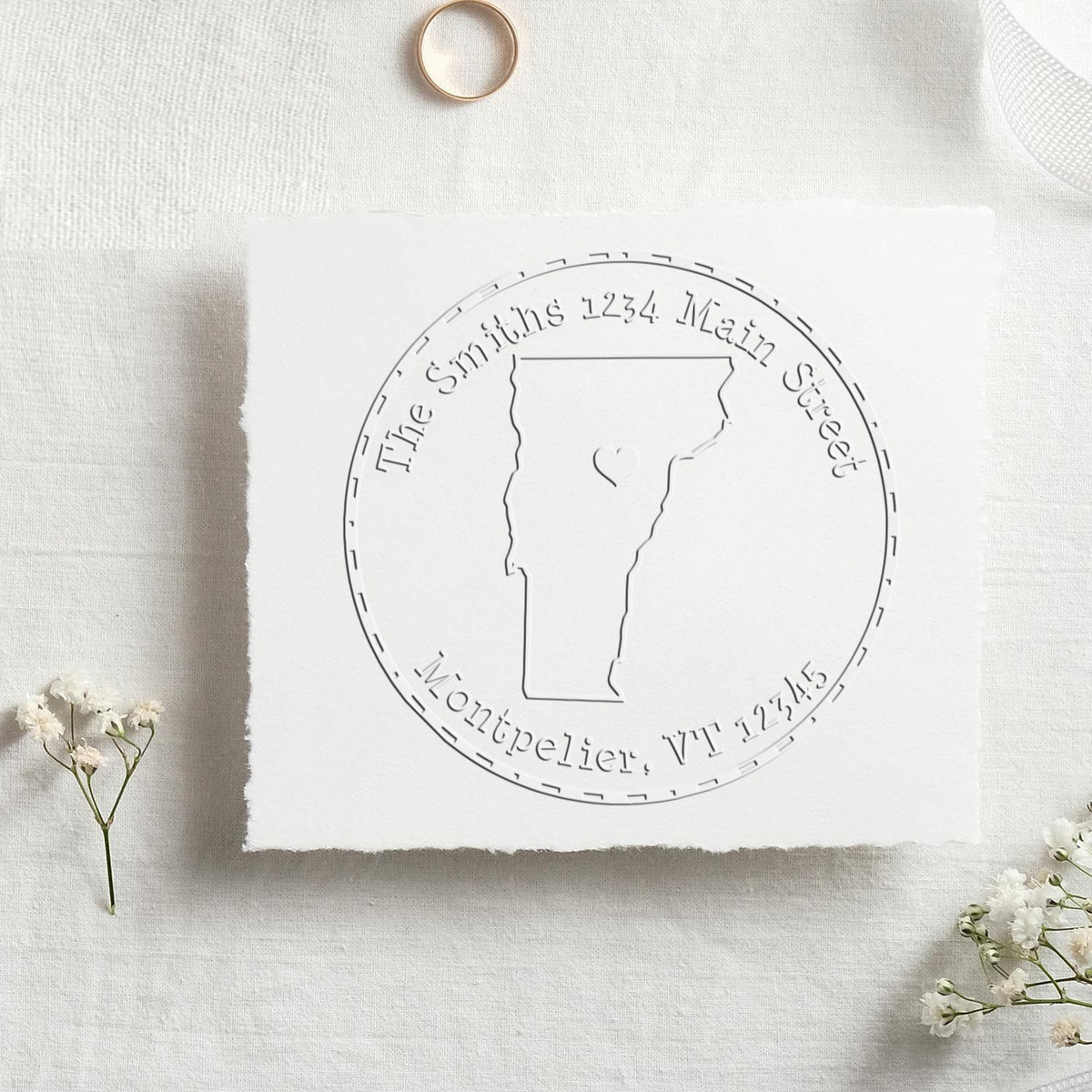 Custom address stamp and seal with Vermont outline on white textured paper, accented by delicate white flowers.