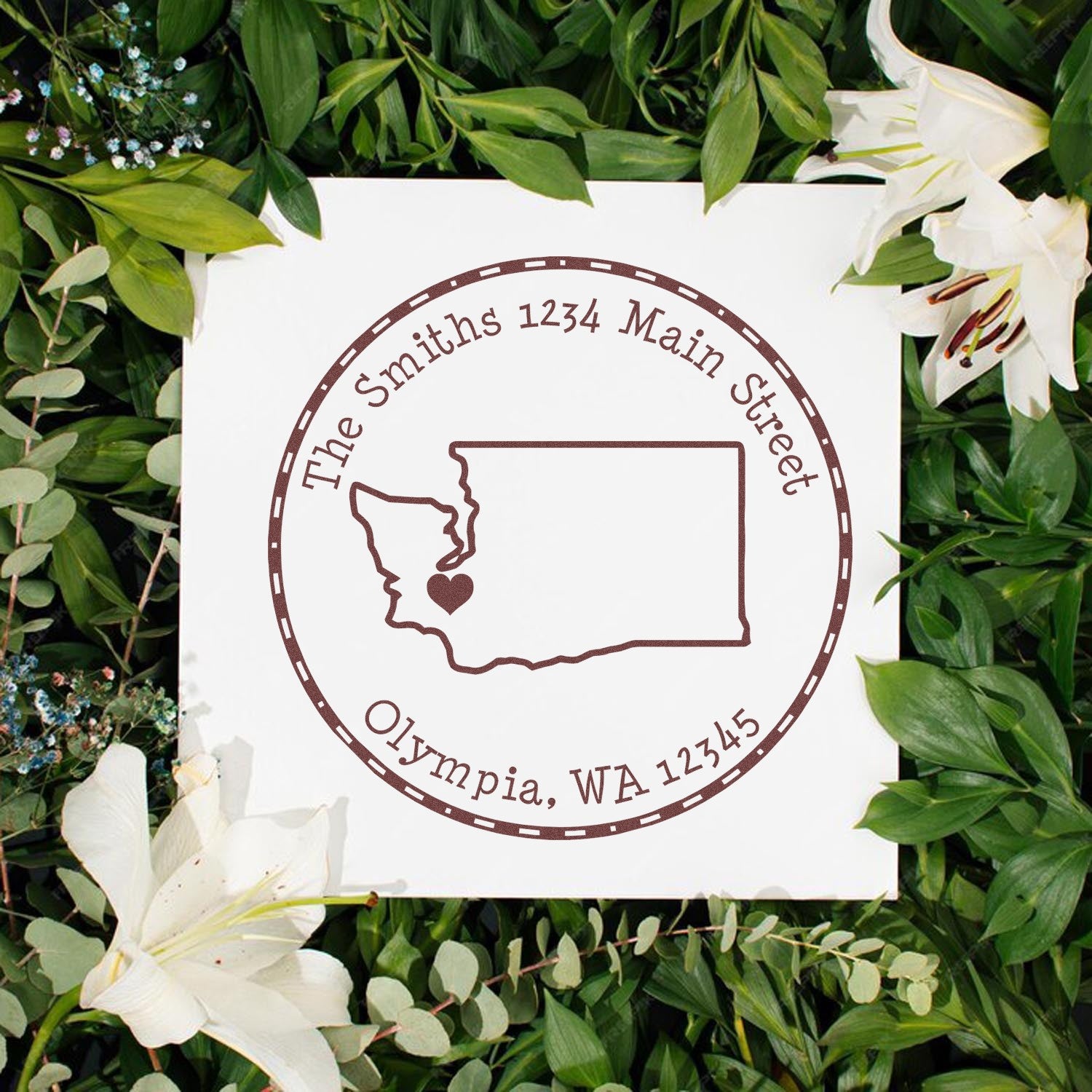 Brown custom stamp seal with Washington outline and heart, reading The Smiths 1234 Main Street, on white card with green leaves and white lilies.