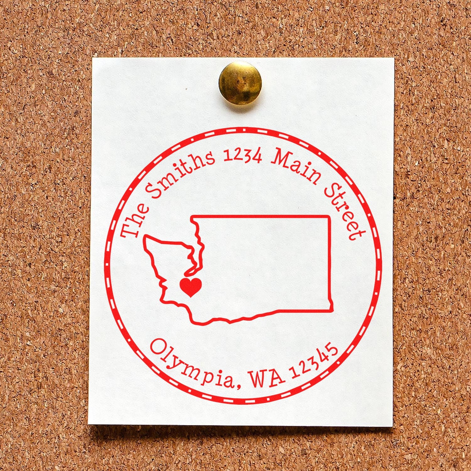 Red circular custom address stamp seal on white card, showing Washington outline, pinned to cork board with brass tack.