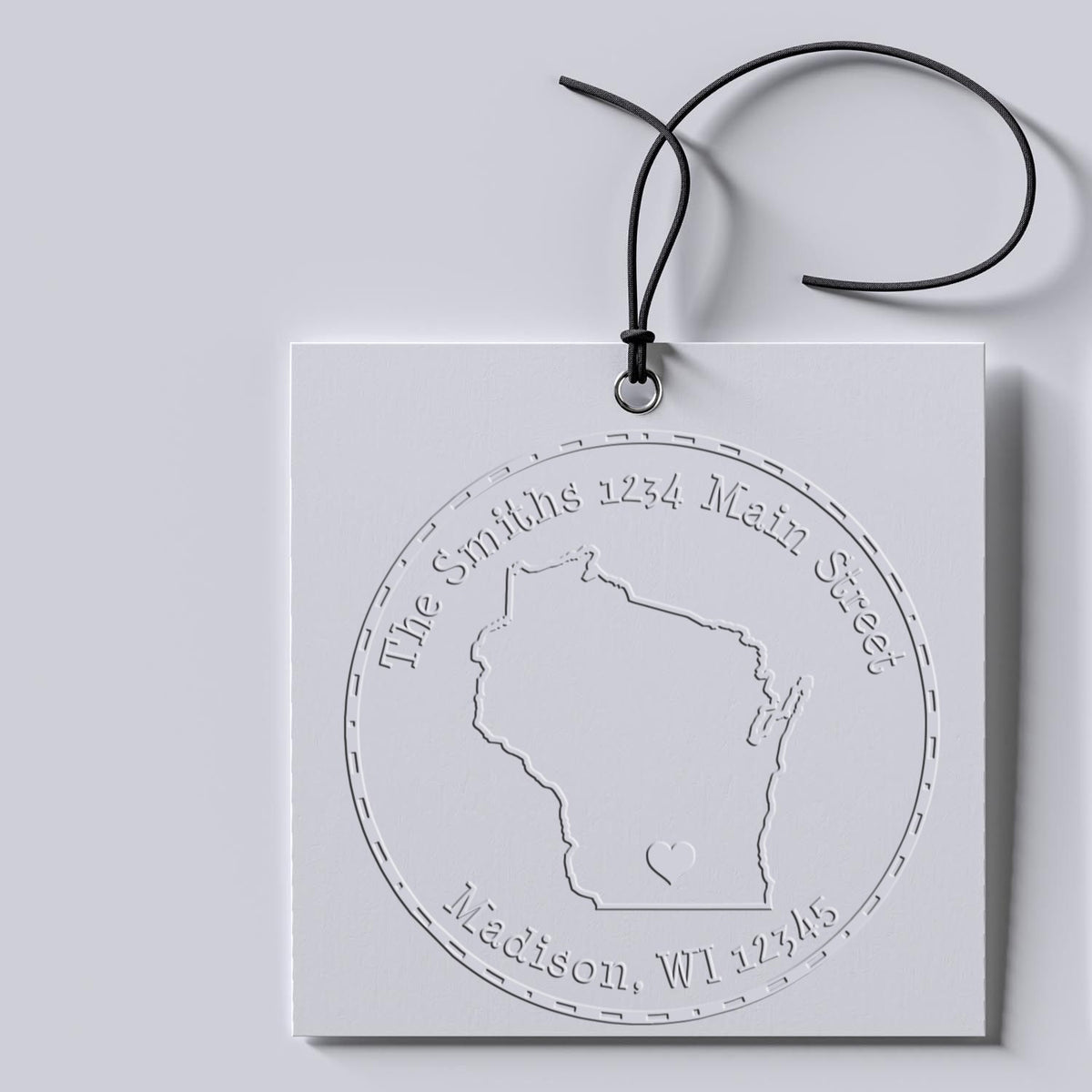 White custom embossing seal with black cord, embossed Wisconsin outline and address on a light gray background.