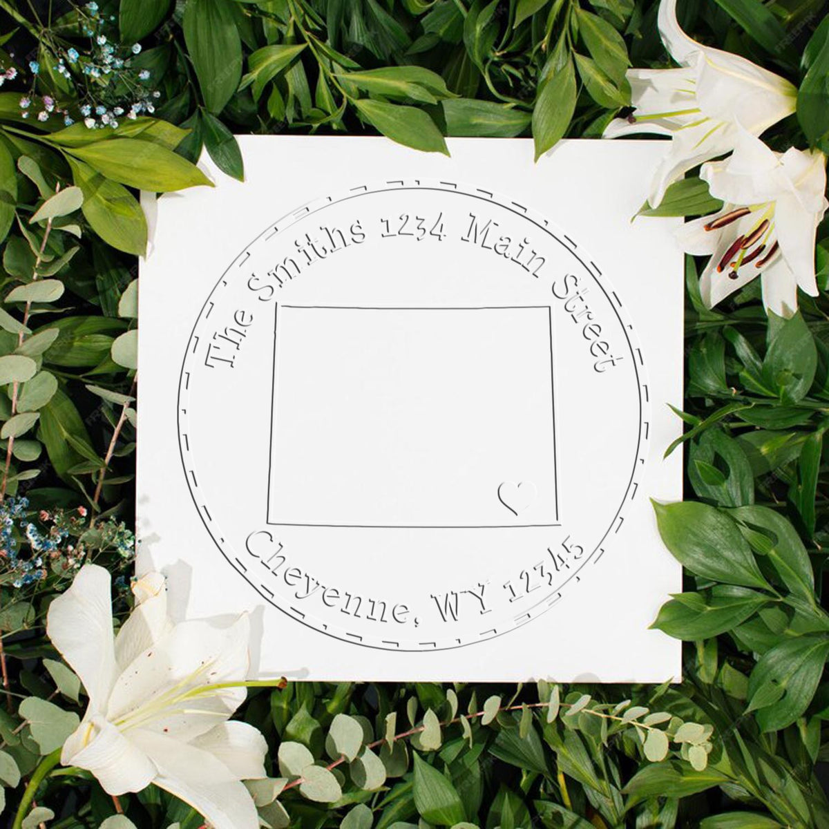 Custom round stamp seal with engraved name, centered on white square, framed by green leaves and white lilies.