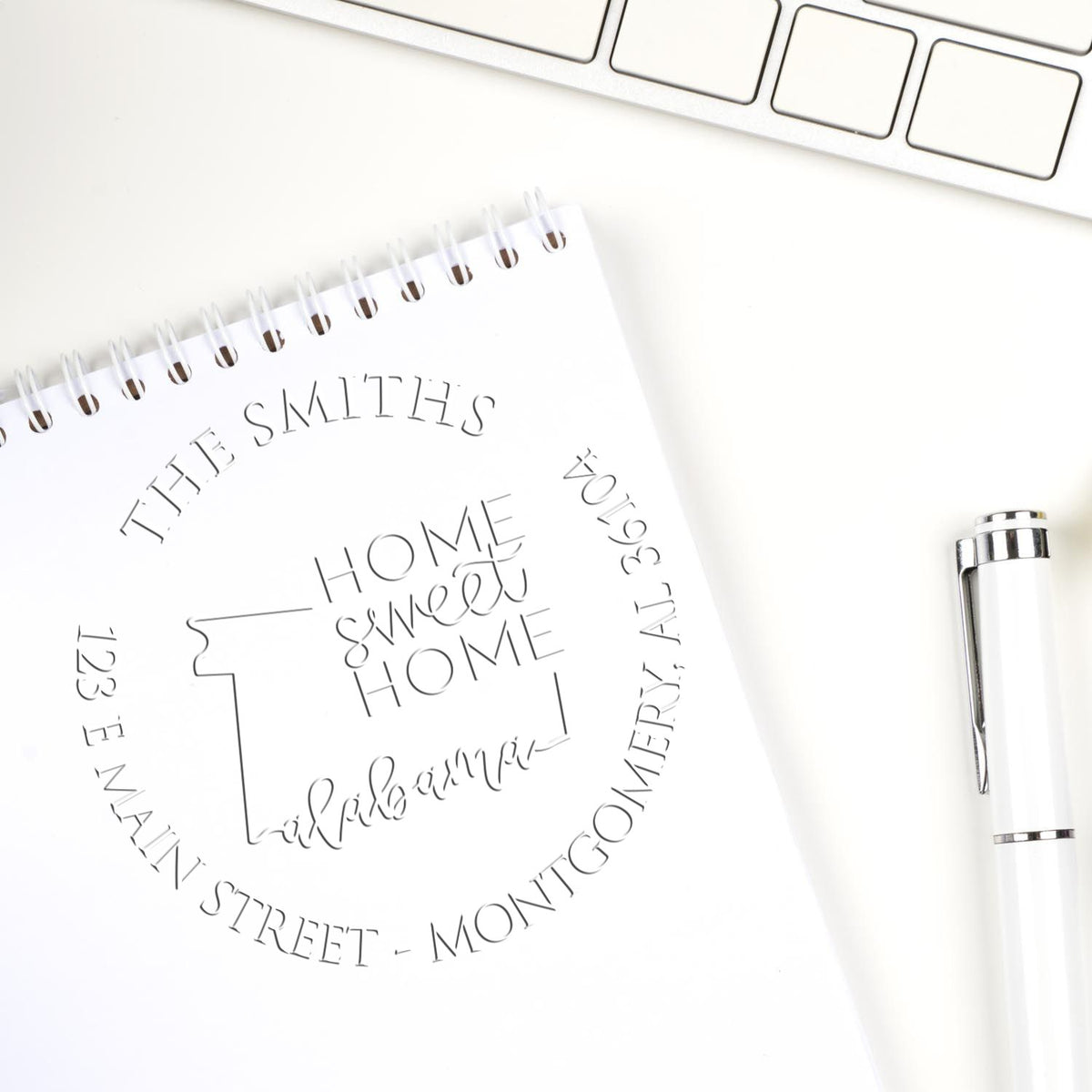 Shiny Round AL Soft Personalized Mailing Address Seal Embosser with State Love Stamps design in use on mailing paper.
