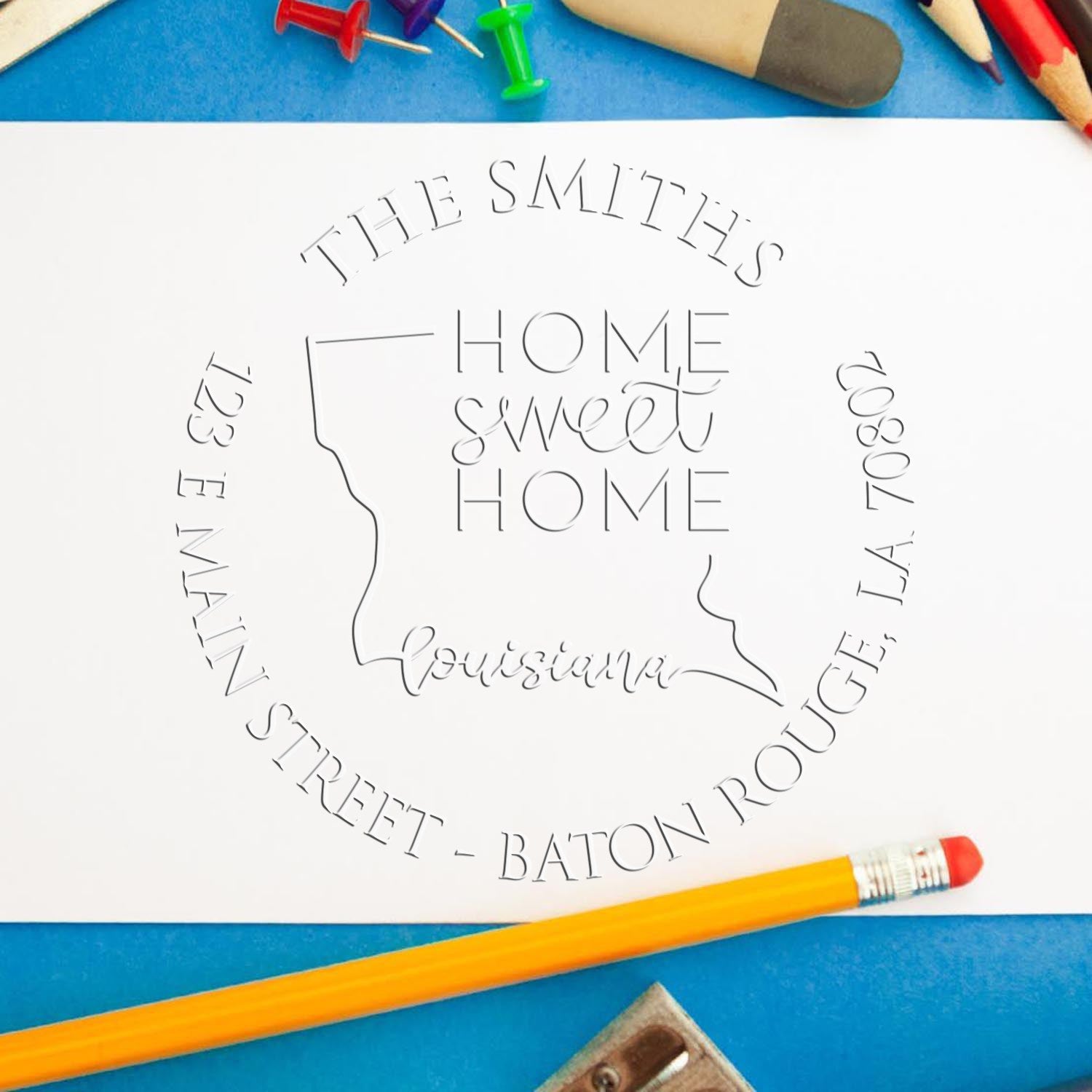 White custom stamp and seal design with Louisiana outline and The Smiths Home Sweet Home, on a blue background with pencils.