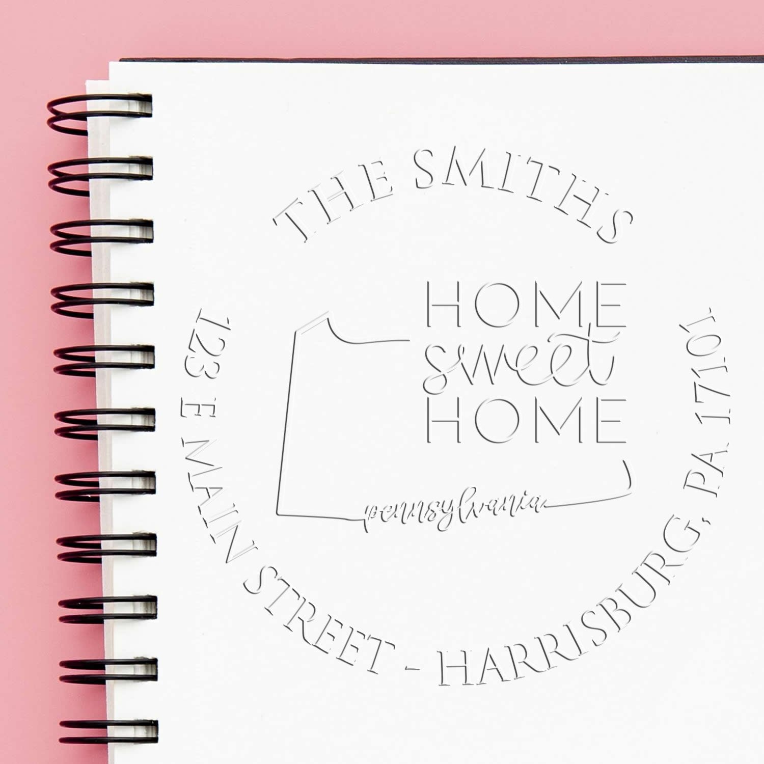 White spiral notebook-style stamp and seal design on pink background, with The Smiths home sweet home and address text.