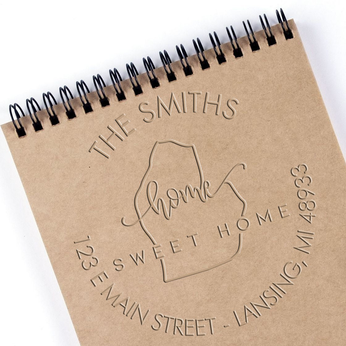 Brown kraft spiral notebook with embossed custom stamp seal, reading The Smiths Home Sweet Home and address details.