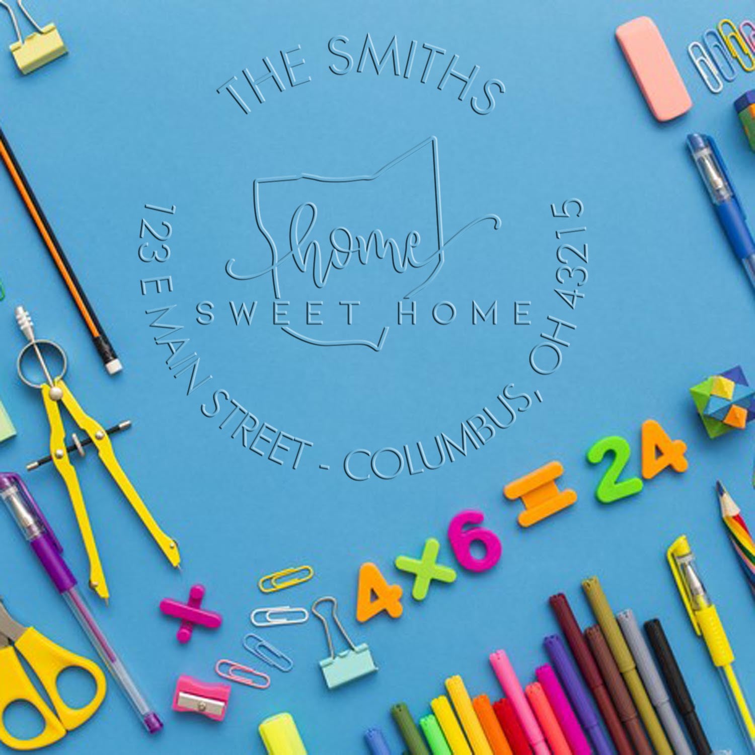 Blue embossed custom stamp seal for The Smiths Sweet Home, framed by colorful school supplies and stationery.