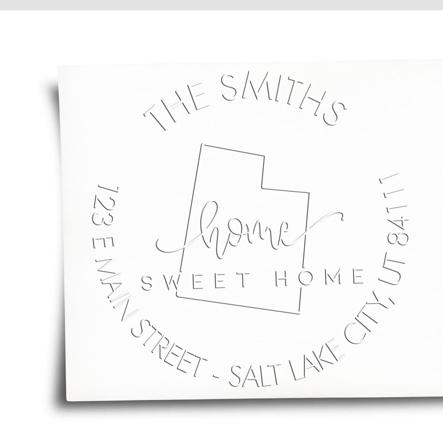 White custom stamp and seal featuring thin gray embossed text, house outline, and circular logo for The Smiths Sweet Home.