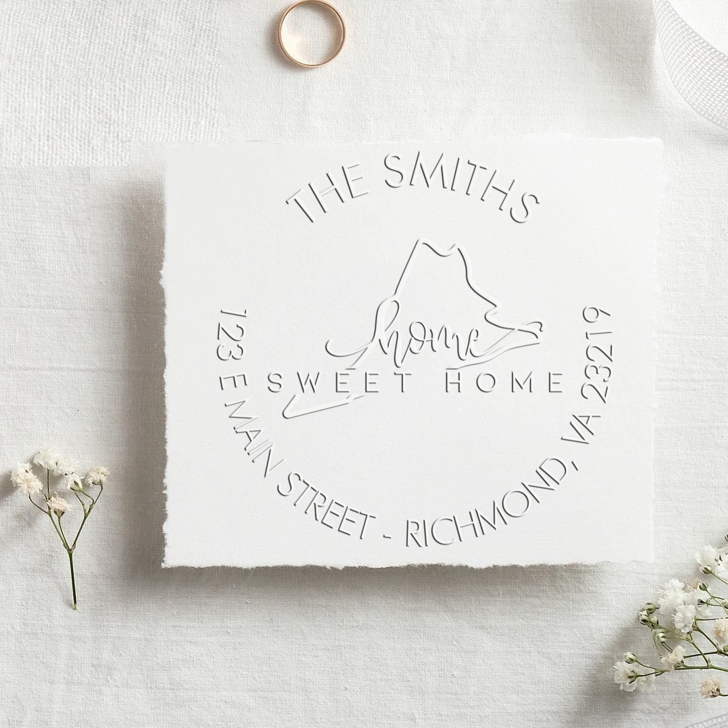 White embossed custom stamp seal for The Smiths Sweet Home on white fabric, with circular address text and small white flowers.