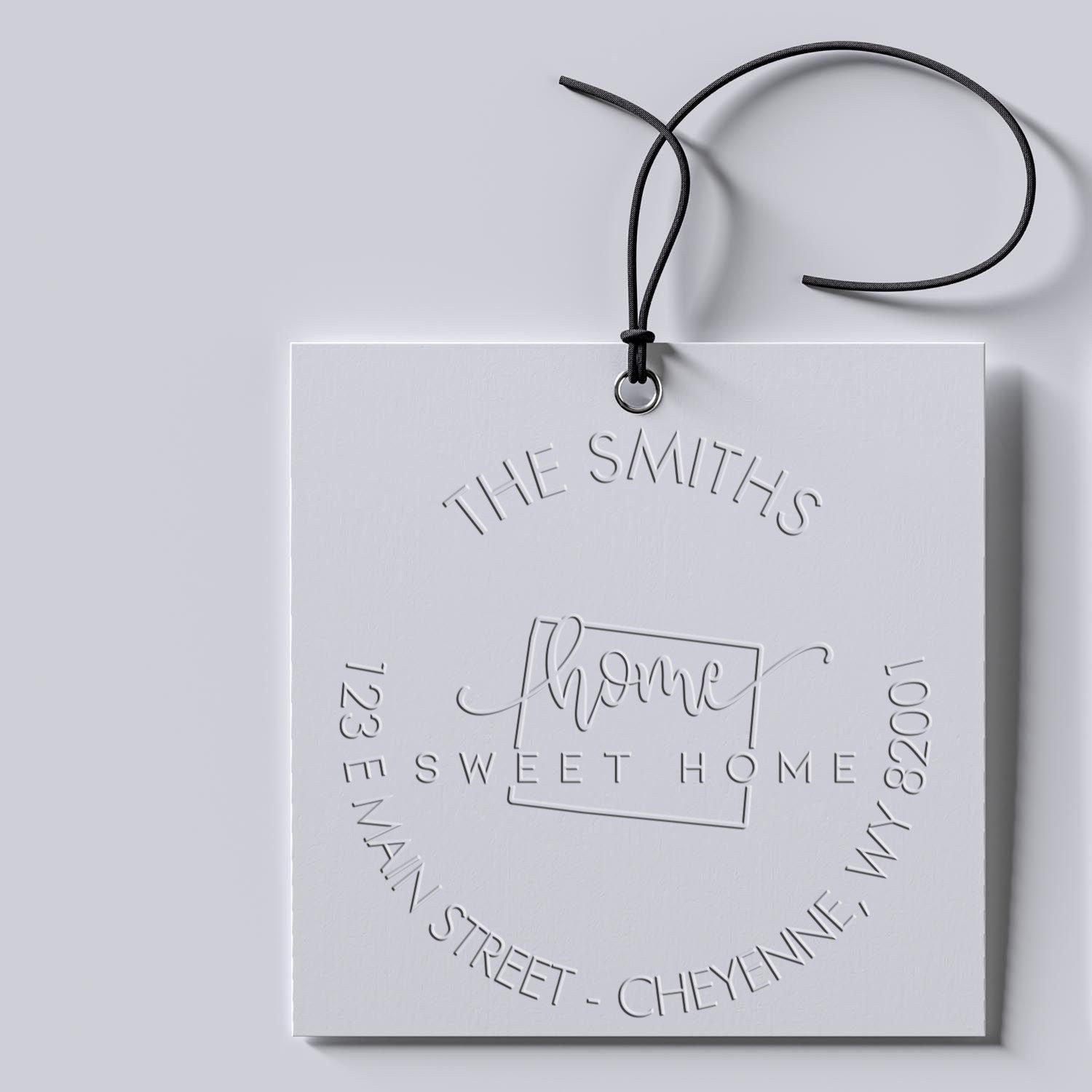White embossed stamp and seal card with black cord, silver-gray lettering, and home sweet home custom branding.