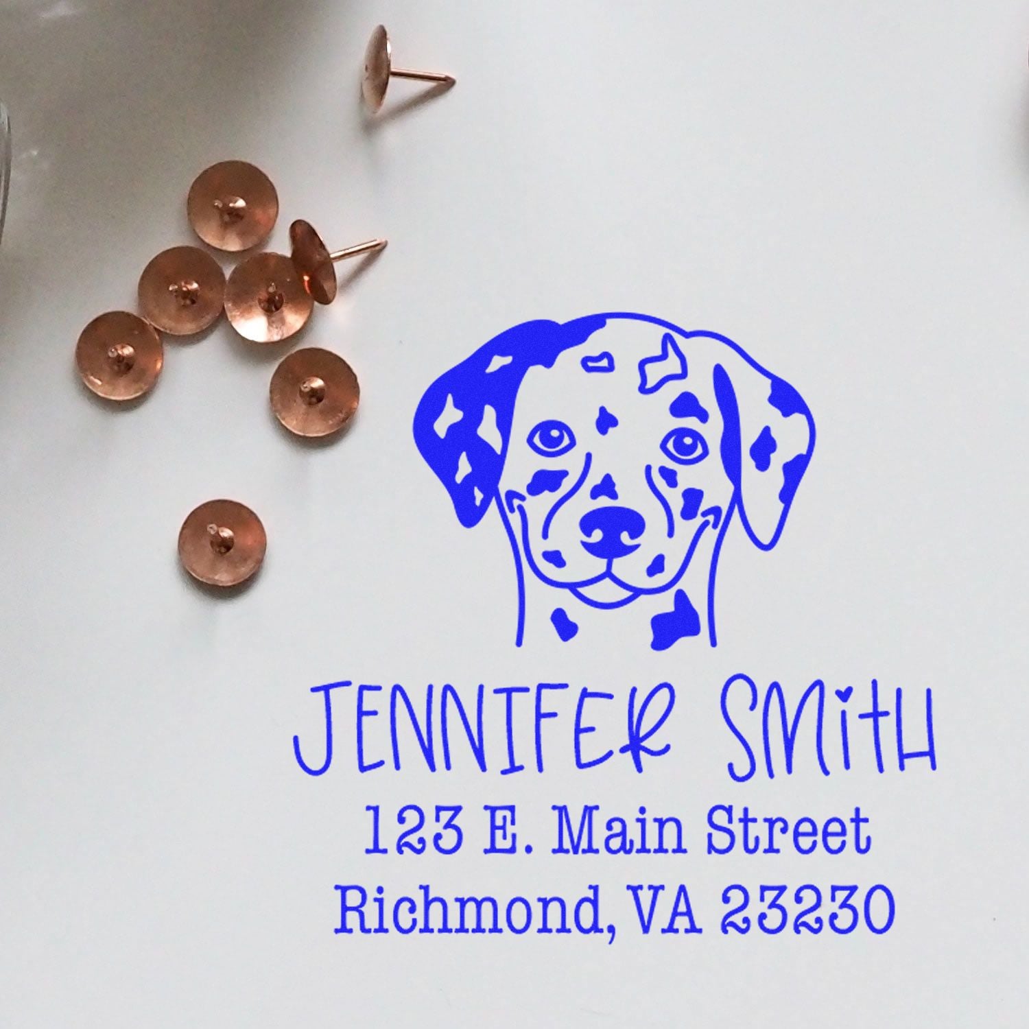 Blue custom address stamp with Dalmatian logo and Jennifer Smith address, beside copper stamp and seal blanks on white background.