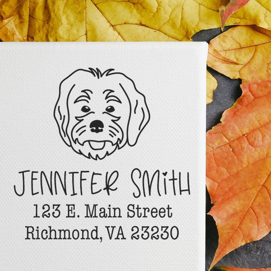 Black custom address stamp/seal with dog logo and Jennifer Smith text on white textured card, on yellow-orange autumn leaves.