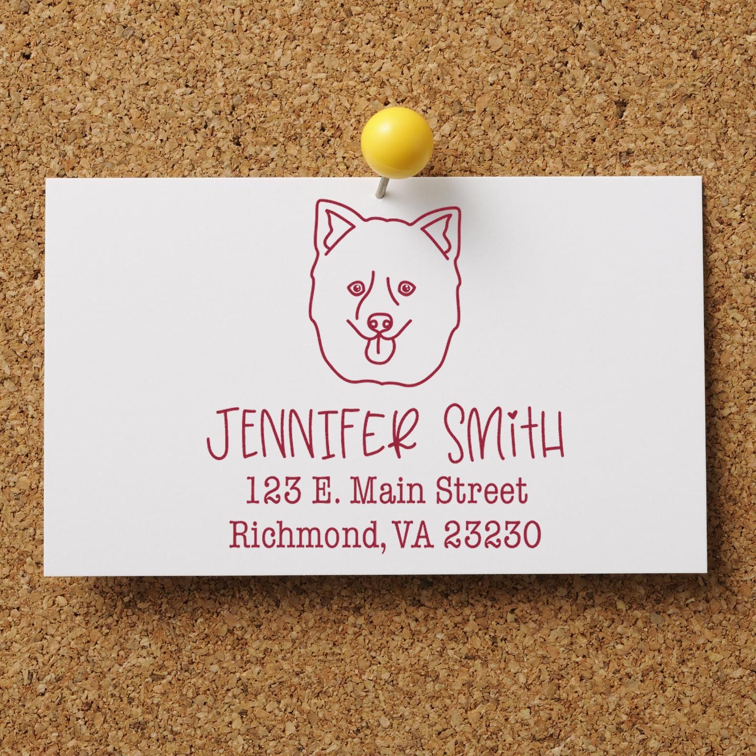 White stamp seal card pinned with yellow tack on corkboard, featuring a red dog head logo, Jennifer Smith name and address.