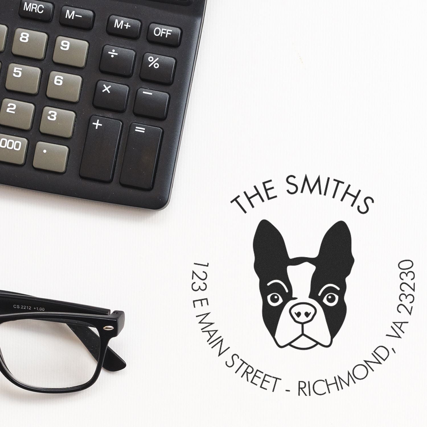 Black custom stamp and seal for The Smiths, with dog logo and address, on white beside a calculator and eyeglasses.