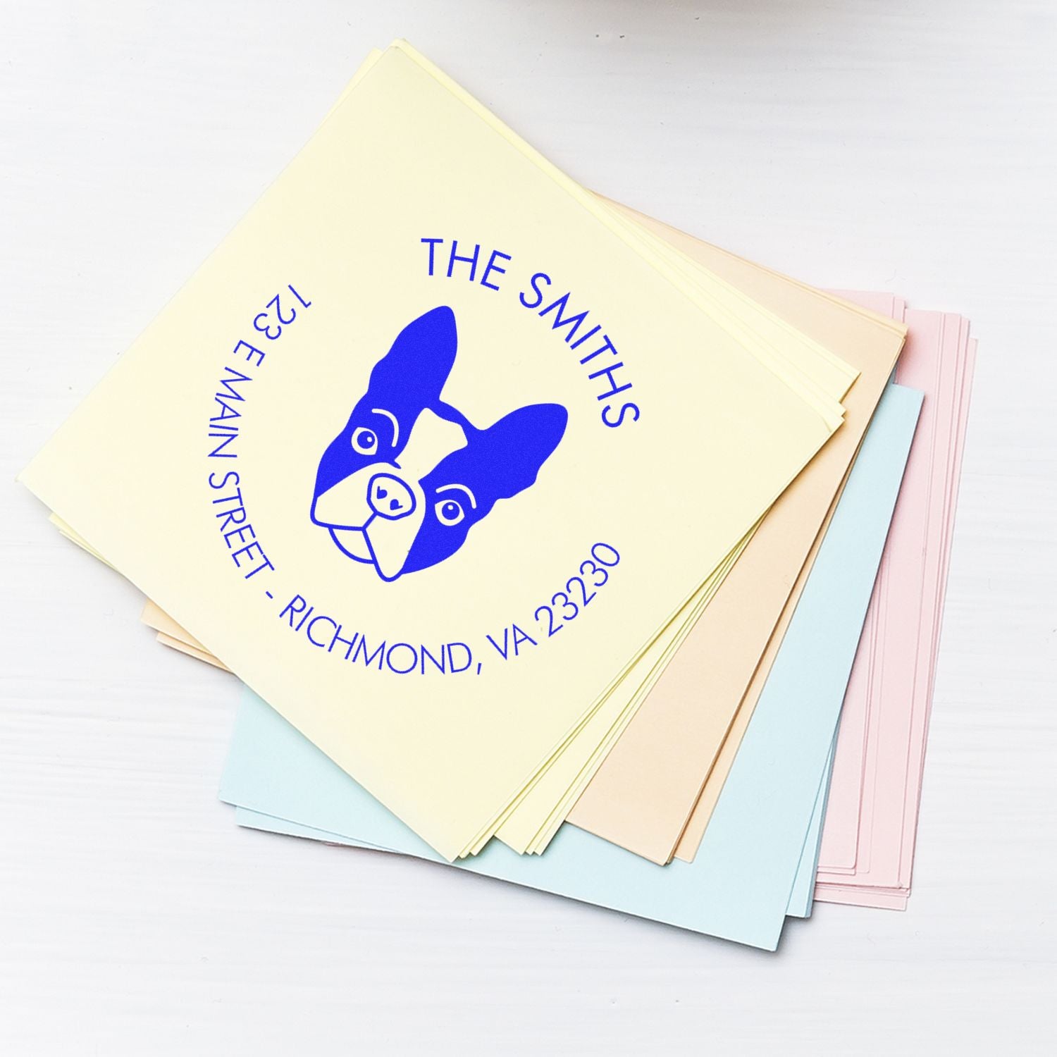 Pastel custom stamp and seal cards with blue dog logo and The Smiths address on cream, pink, blue, and peach sheets