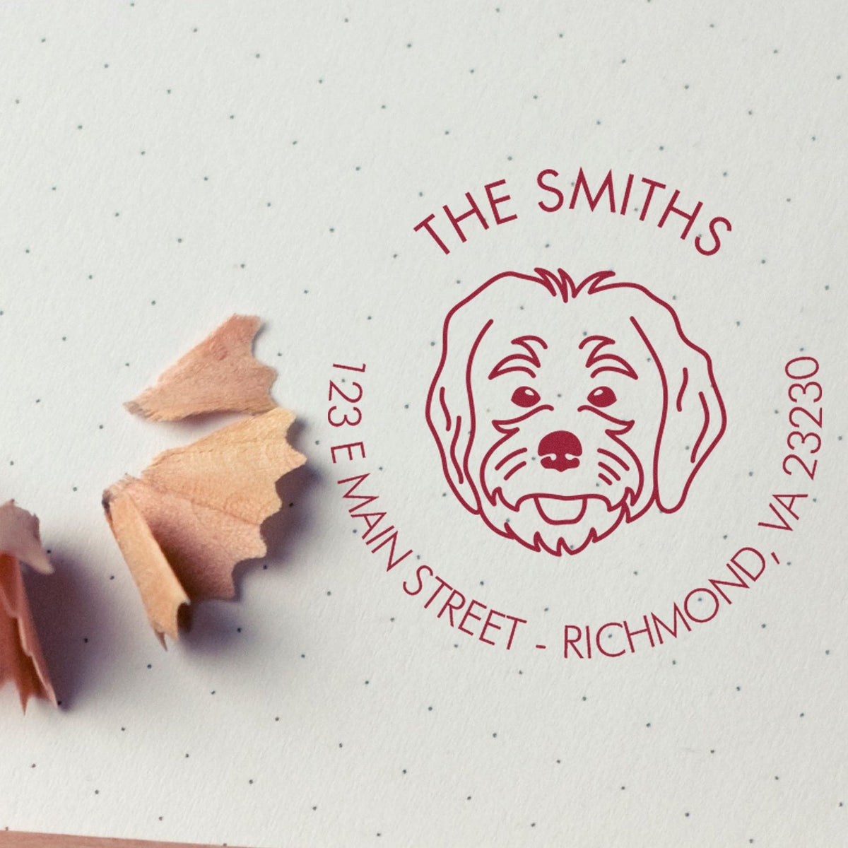 Red custom dog address stamp seal on white dotted paper with pencil shavings, reading The Smiths, 123 E Main Street, Richmond, VA 23230