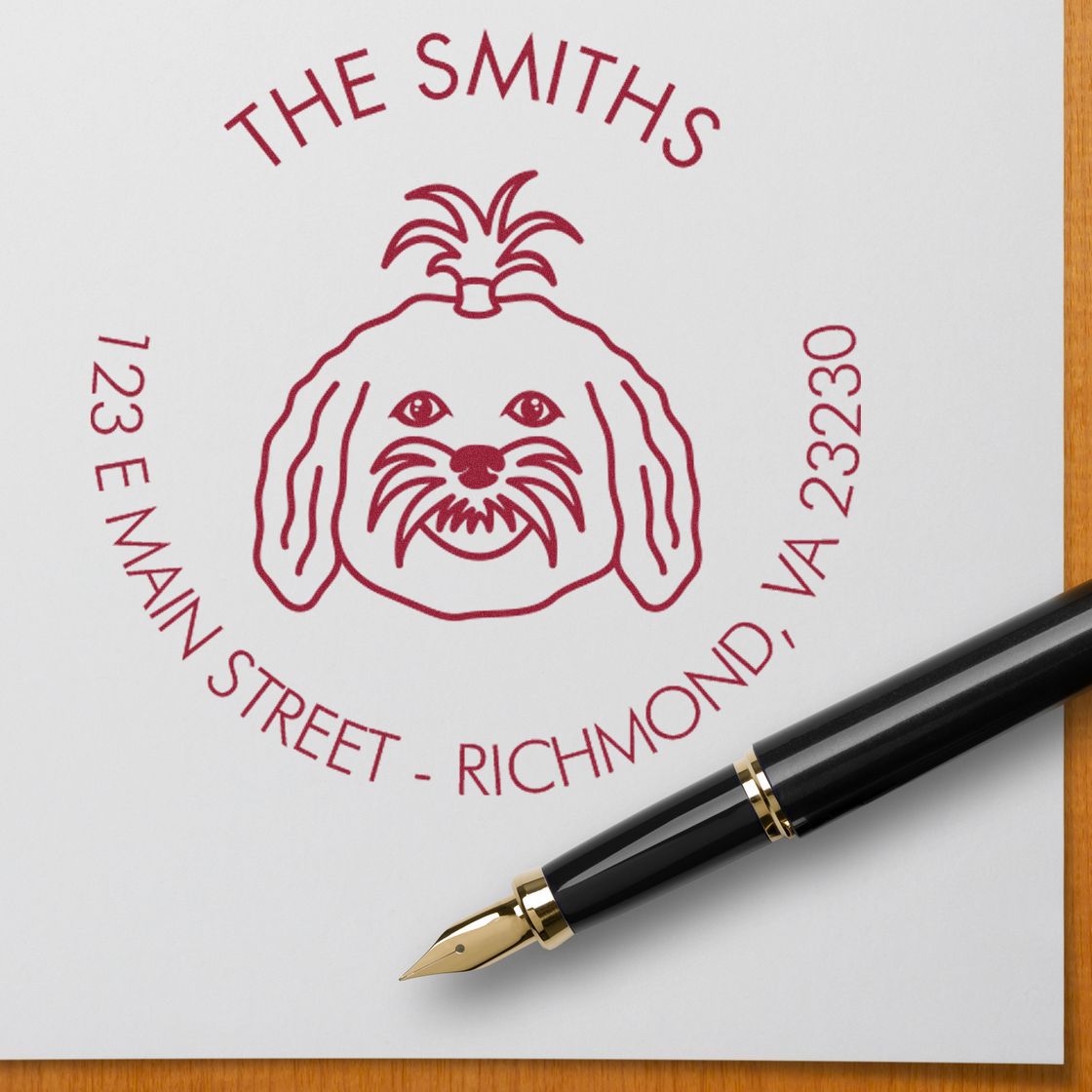 Red dog address stamp seal reading The Smiths, 123 E Main Street, Richmond, VA, with a black fountain pen.