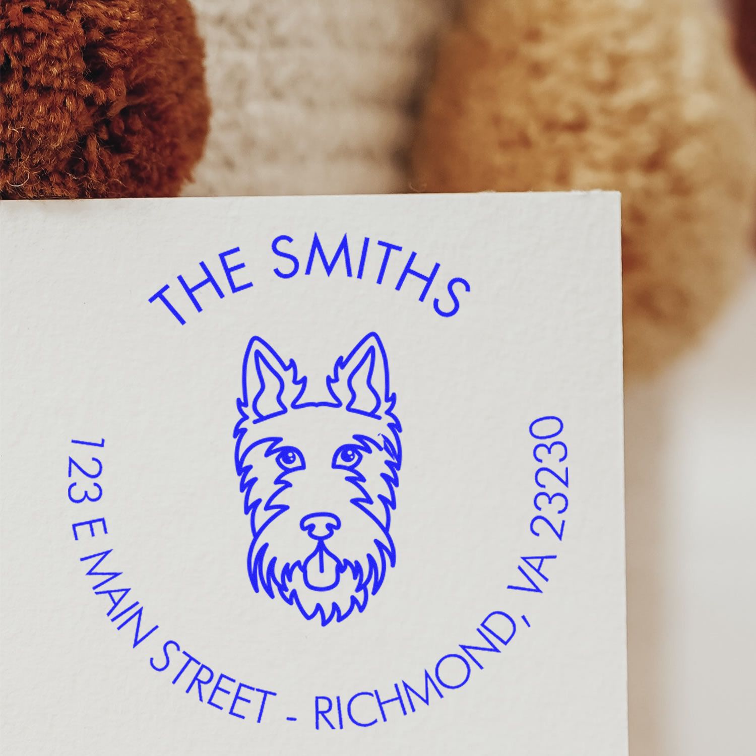Blue custom dog seal stamp with THE SMITHS and 123 E Main Street, Richmond, VA on white paper.