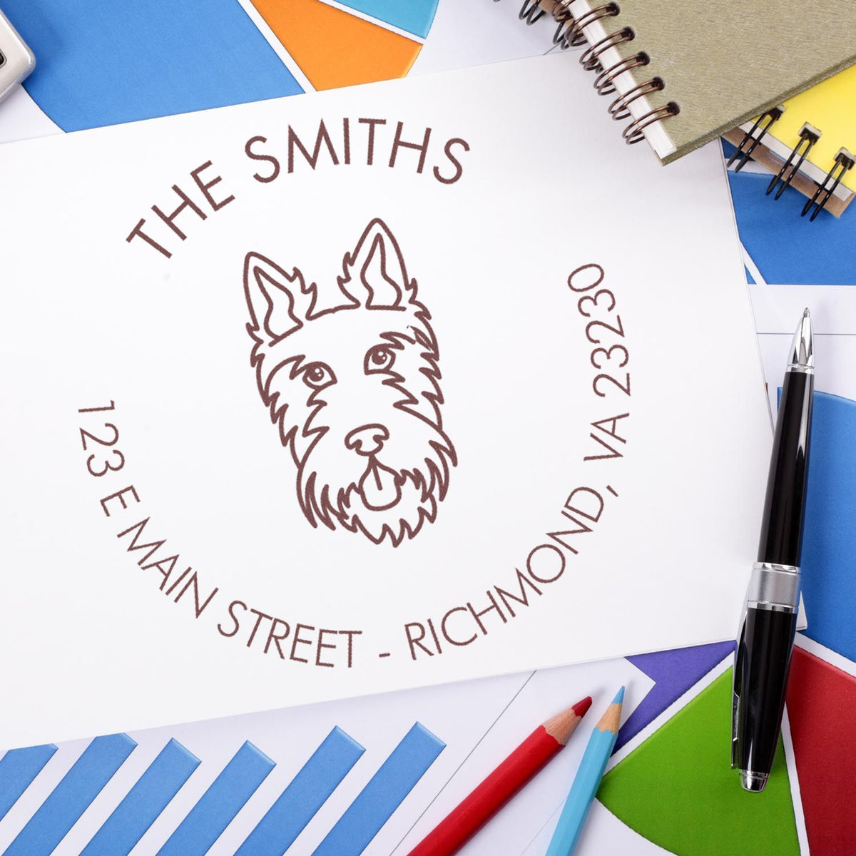 White custom stamp seal with brown dog logo and Richmond address, surrounded by colorful envelopes, pens, and notebooks.