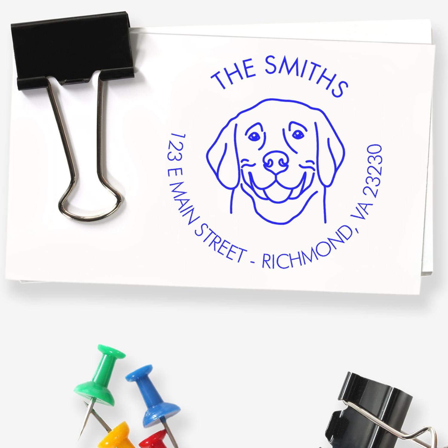 Black binder clip holding white paper with blue custom dog stamp seal reading The Smiths and Richmond, VA address.