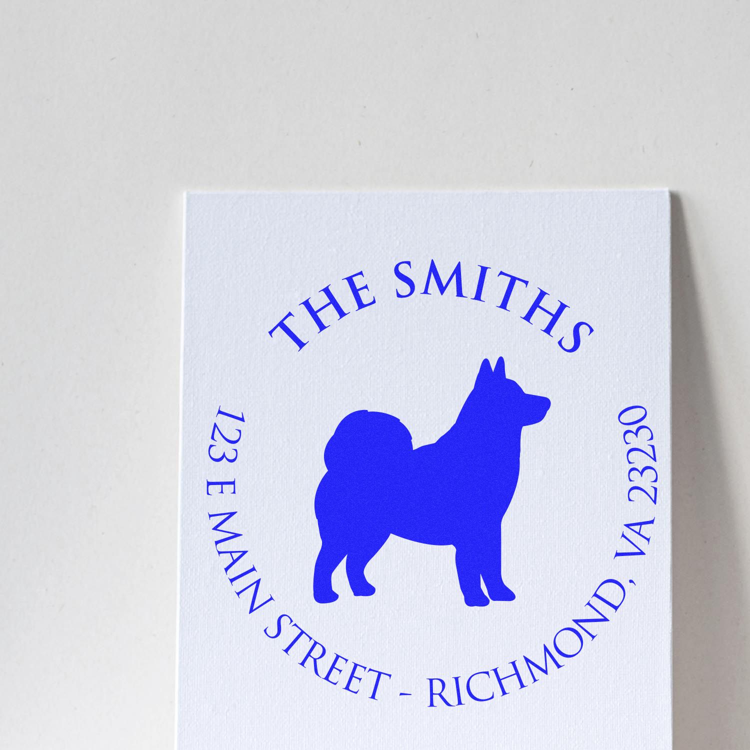 Blue custom address stamp seal with dog silhouette on white card, reading The Smiths, 123 E Main Street, Richmond, VA 23230.