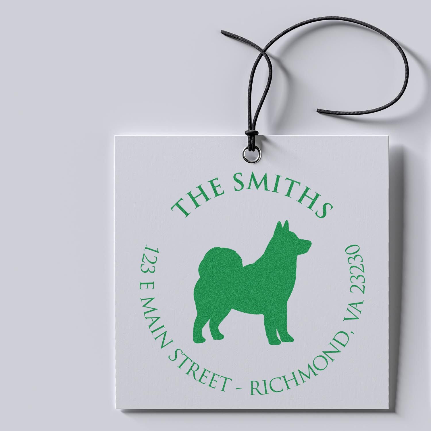 Custom green stamp and seal tag with dog silhouette, The Smiths, address, and black hanging cord on white card.