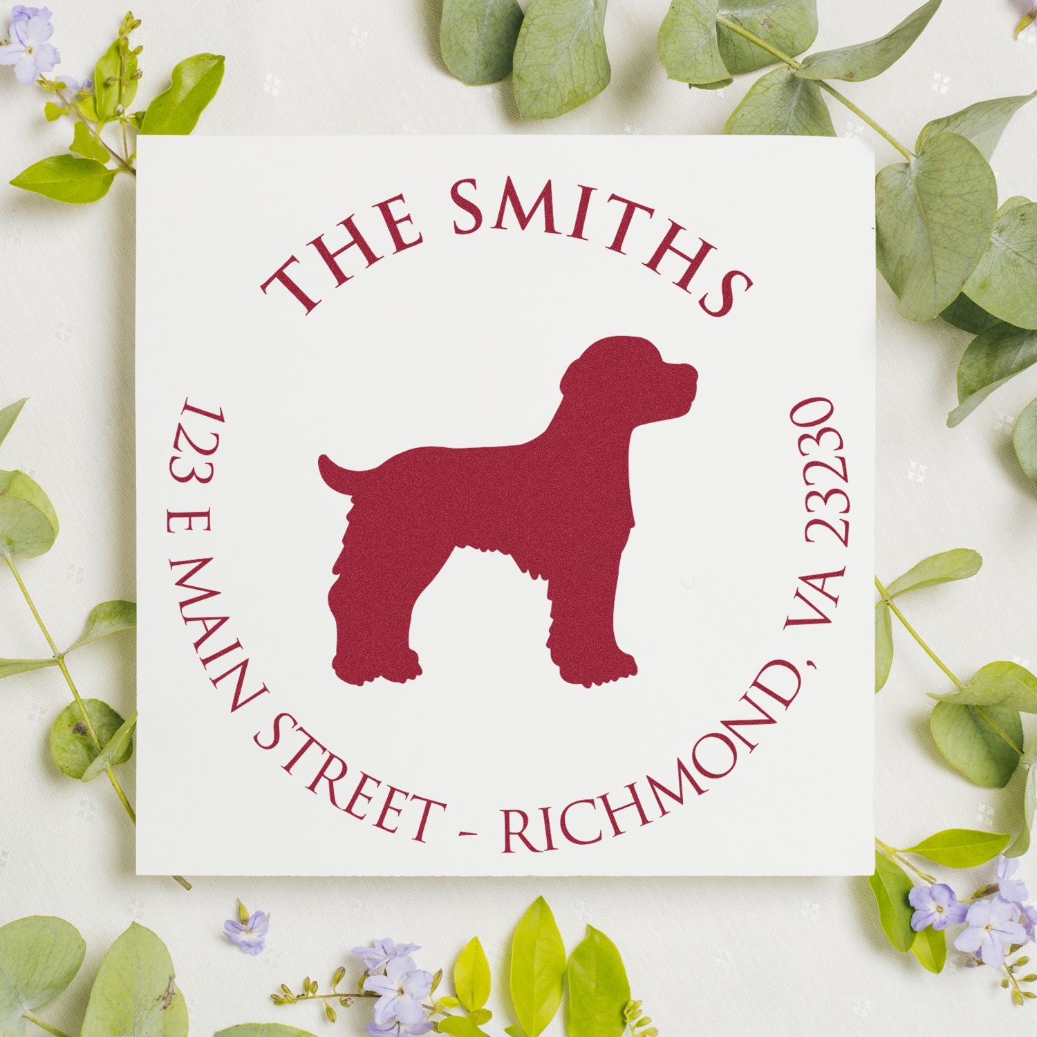 Burgundy custom dog stamp seal with The Smiths, 123 E Main Street, Richmond, VA 23230 on a white card with green leaves.