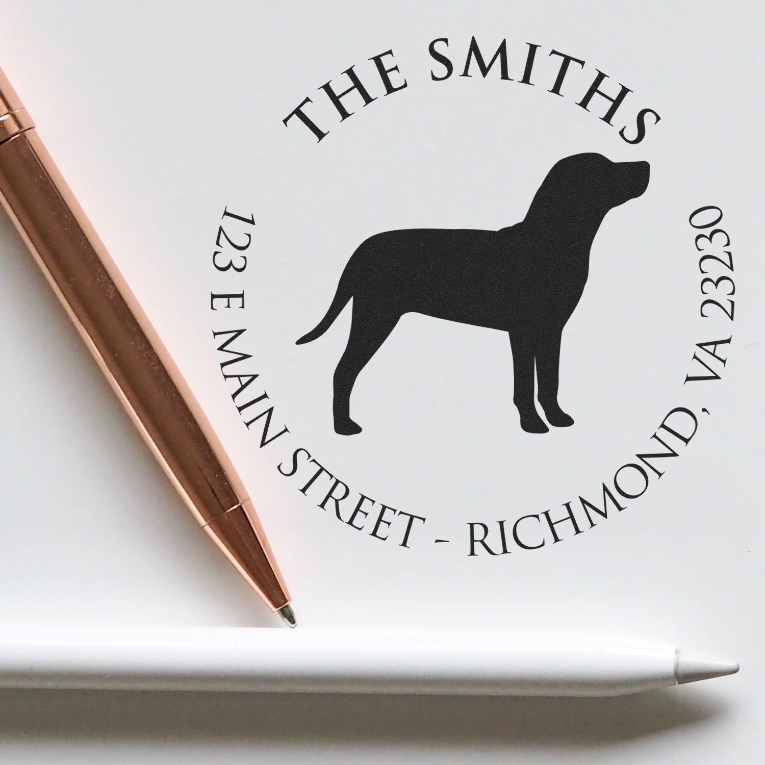 Custom return address stamp and seal with black dog silhouette on white, plus a rose gold pen.