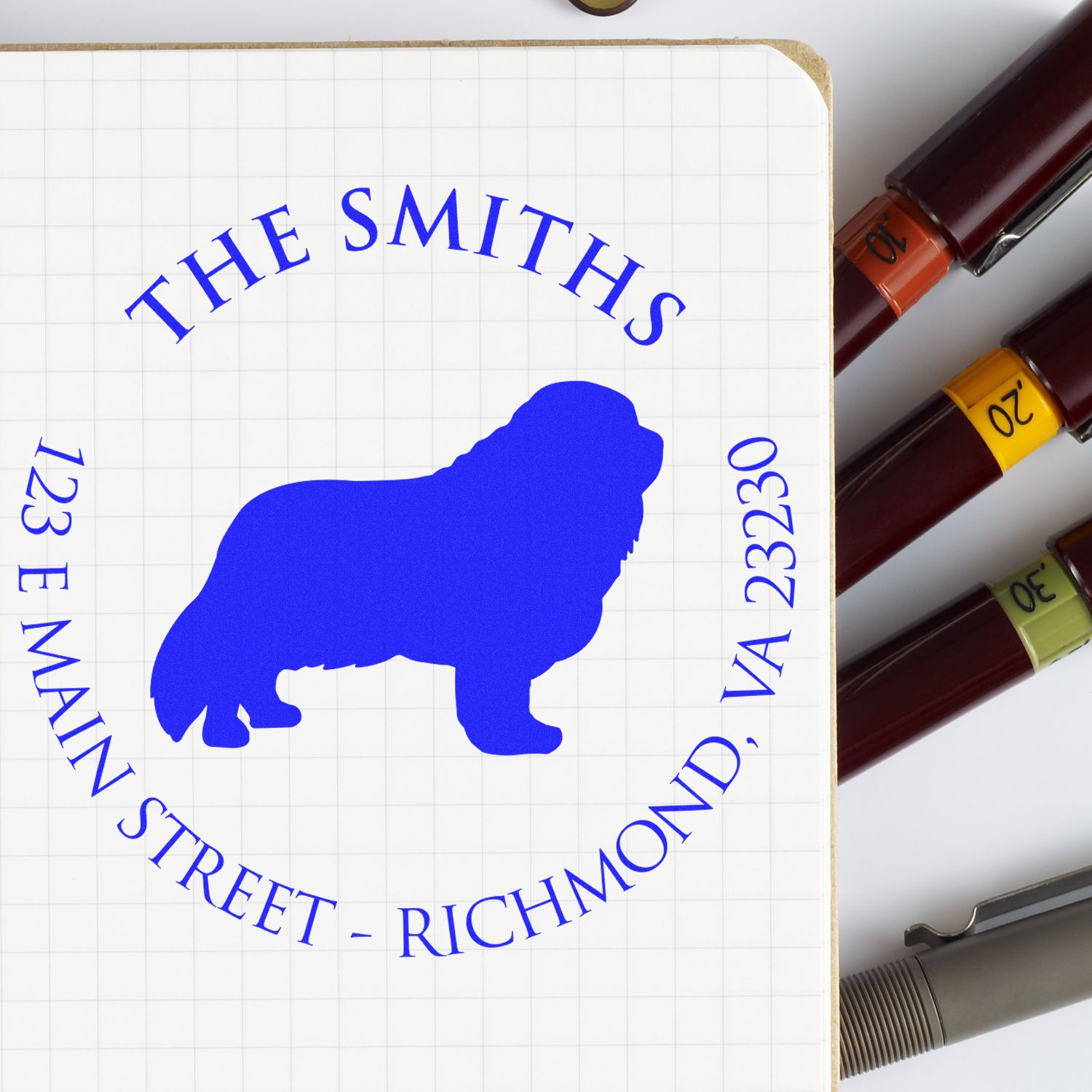 Blue custom stamp seal for The Smiths on graph paper, beside brown date stamps and a silver pen.