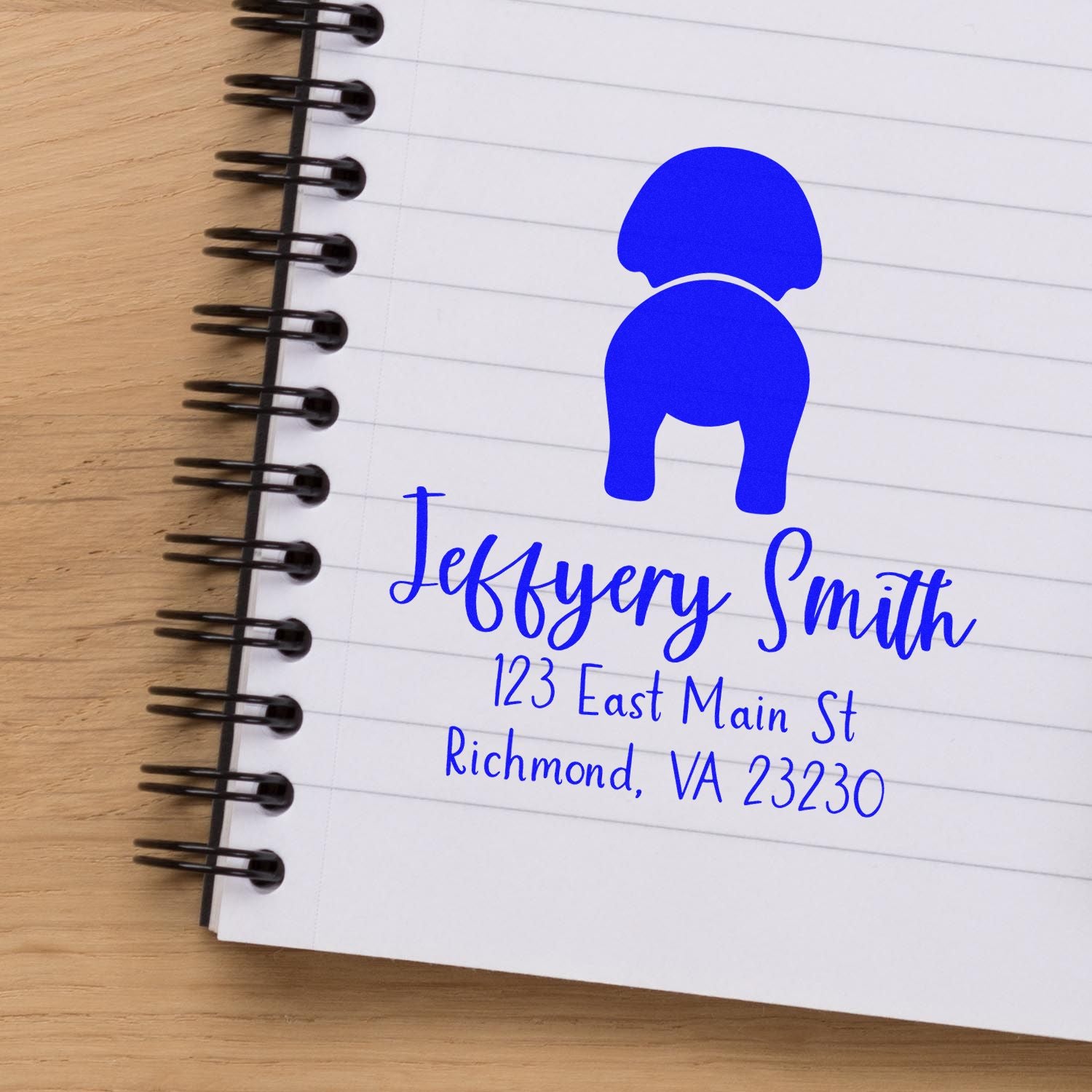 Blue custom stamp and seal for Jefferson Smith with address on a lined spiral notebook.