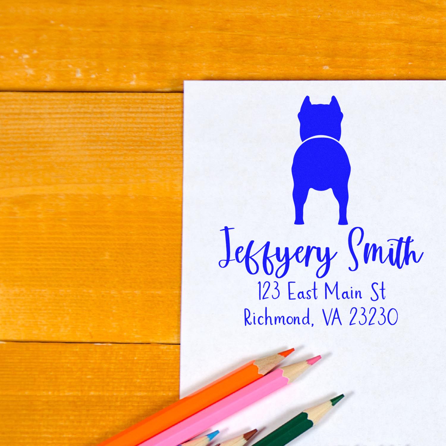 White custom stamp and seal with blue dog logo, Jeffery Smith name and address, on wood with colorful pencils.