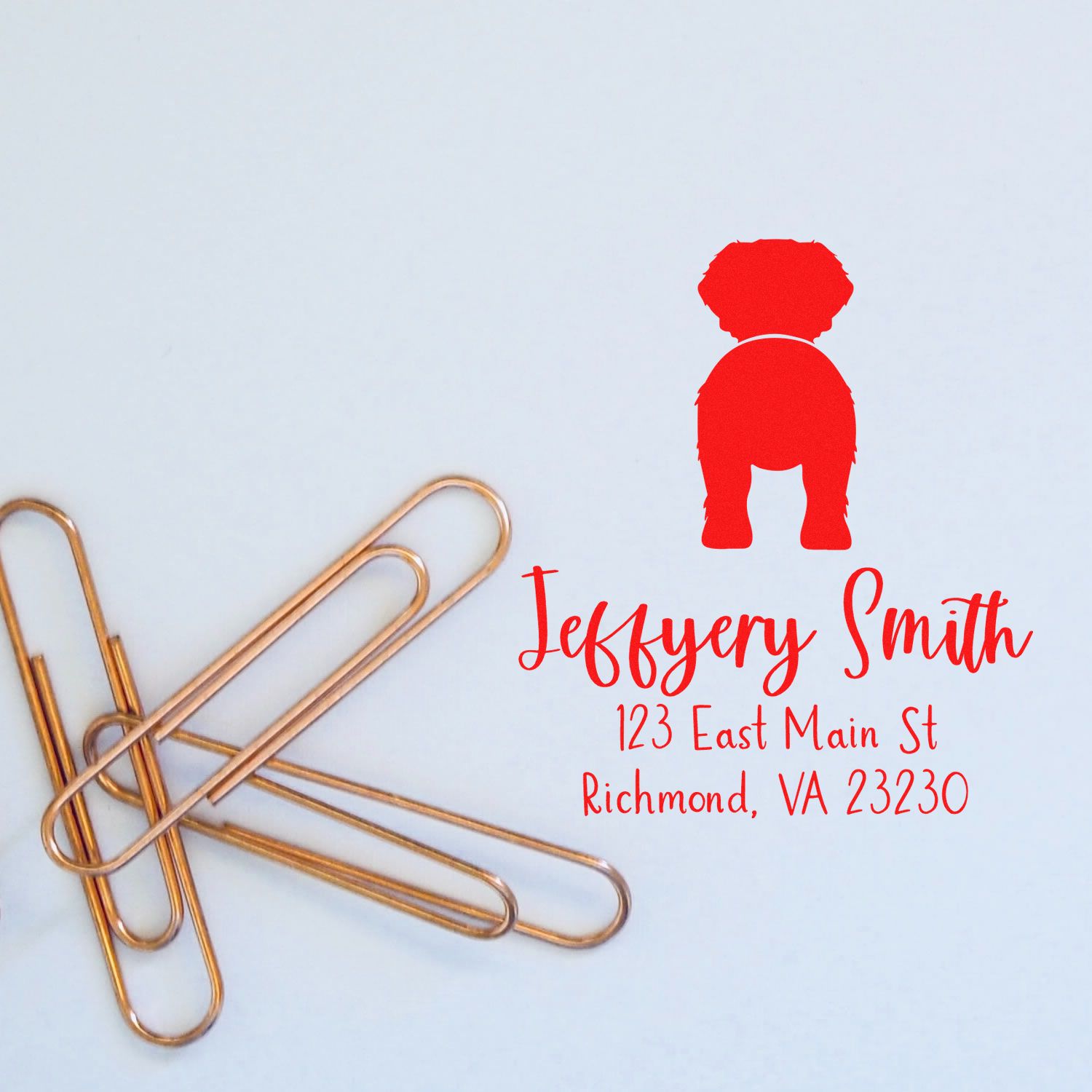 Custom red dog return address stamp and seal design with gold paperclips on a white background