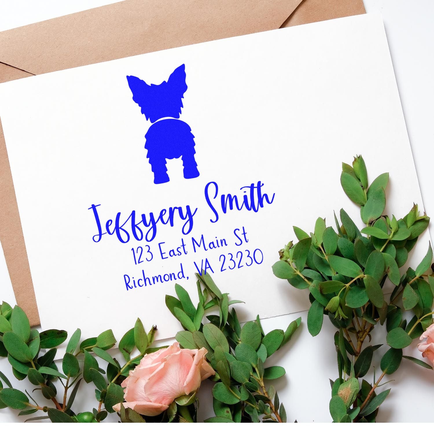 Custom blue dog stamp and seal on white card with name and address, framed by green eucalyptus and pink roses.