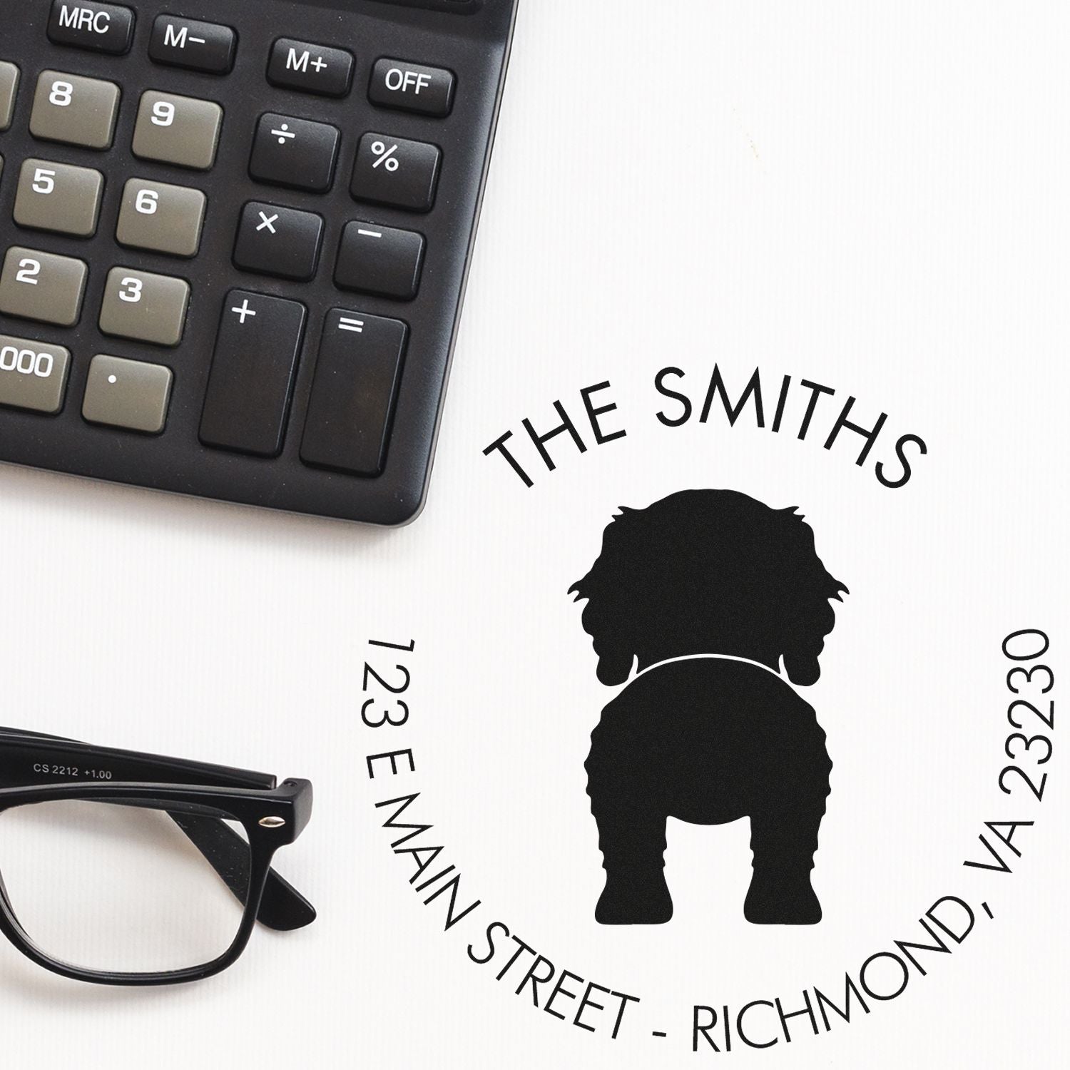 Custom black stamp and seal with dog silhouette, The Smiths address, plus calculator and glasses on white.