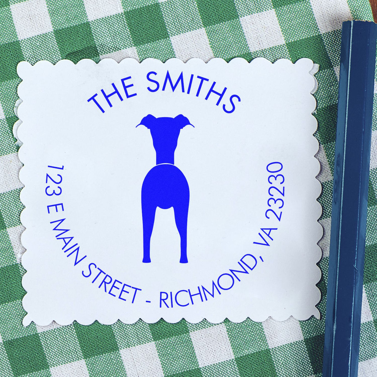 White scalloped custom stamp seal with blue dog logo and The Smiths text on green checkered fabric, beside a blue stamp handle