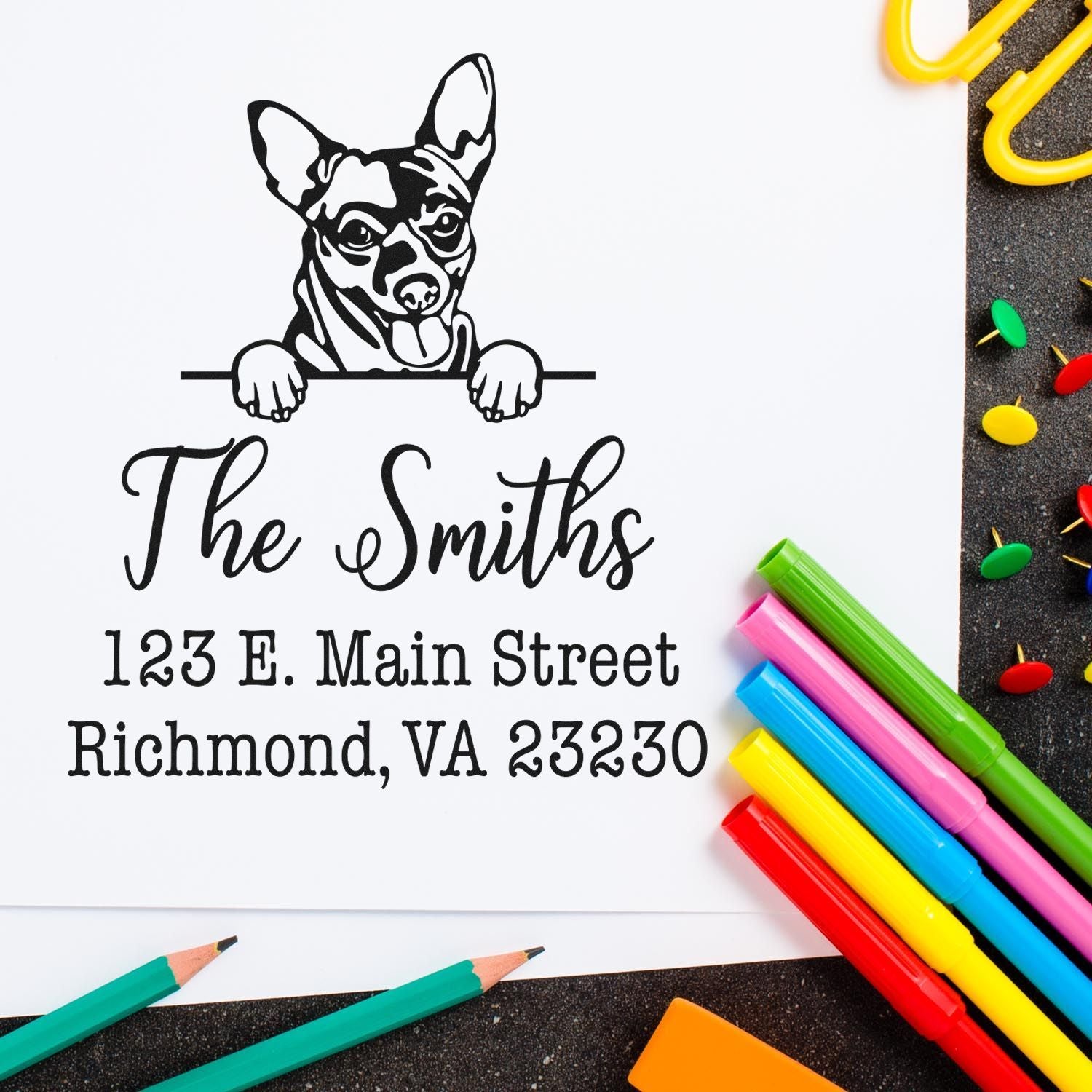 Custom black address stamp with dog logo and ĀThe SmithsĀ over Richmond, VA address, surrounded by colorful pens and pushpins.
