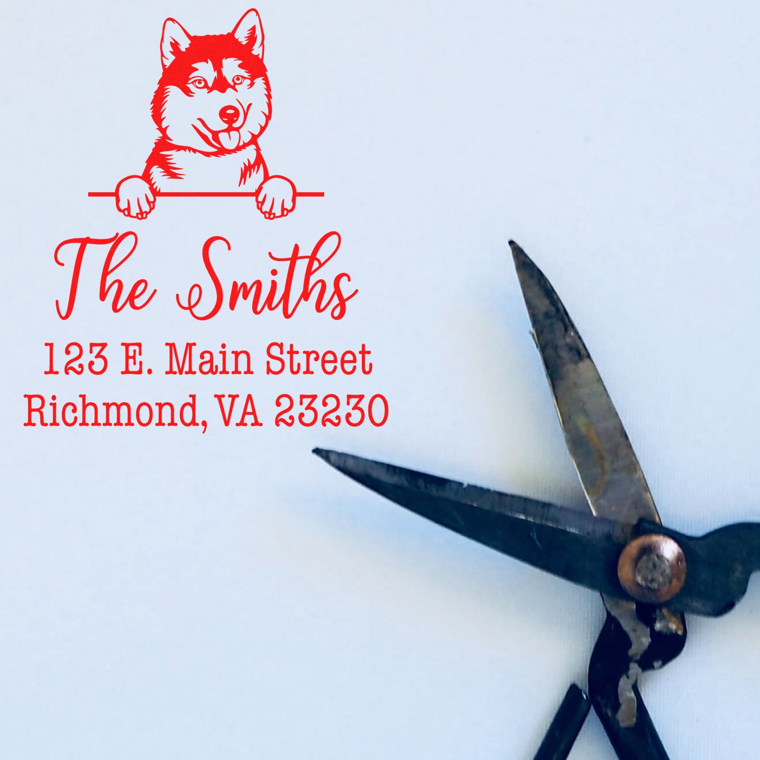 Red custom address stamp with husky logo, The Smiths and Richmond, VA text, beside a black metal stamp-and-seal tool.