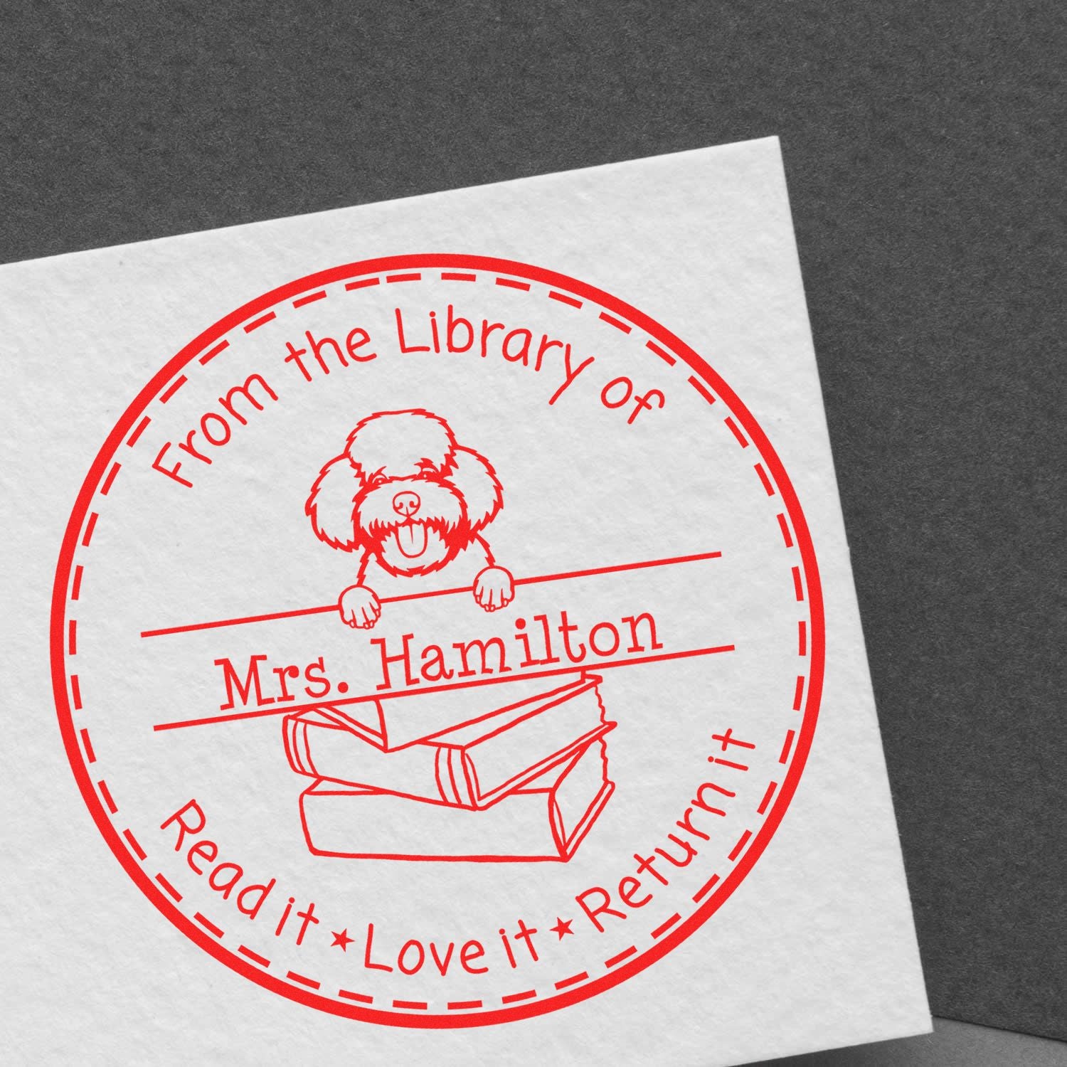 Red circular self-inking library stamp with dog and books, From the Library of Mrs. Hamilton and Read it Love it Return it