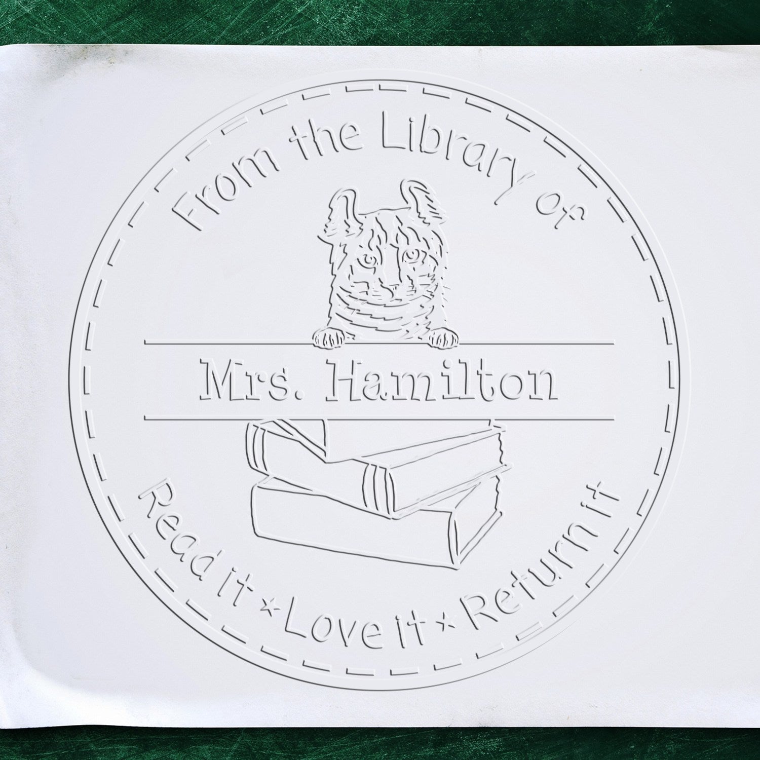 White embossed library stamp and seal with cat on books, reading From the Library of Mrs. Hamilton Read it Love it Return it
