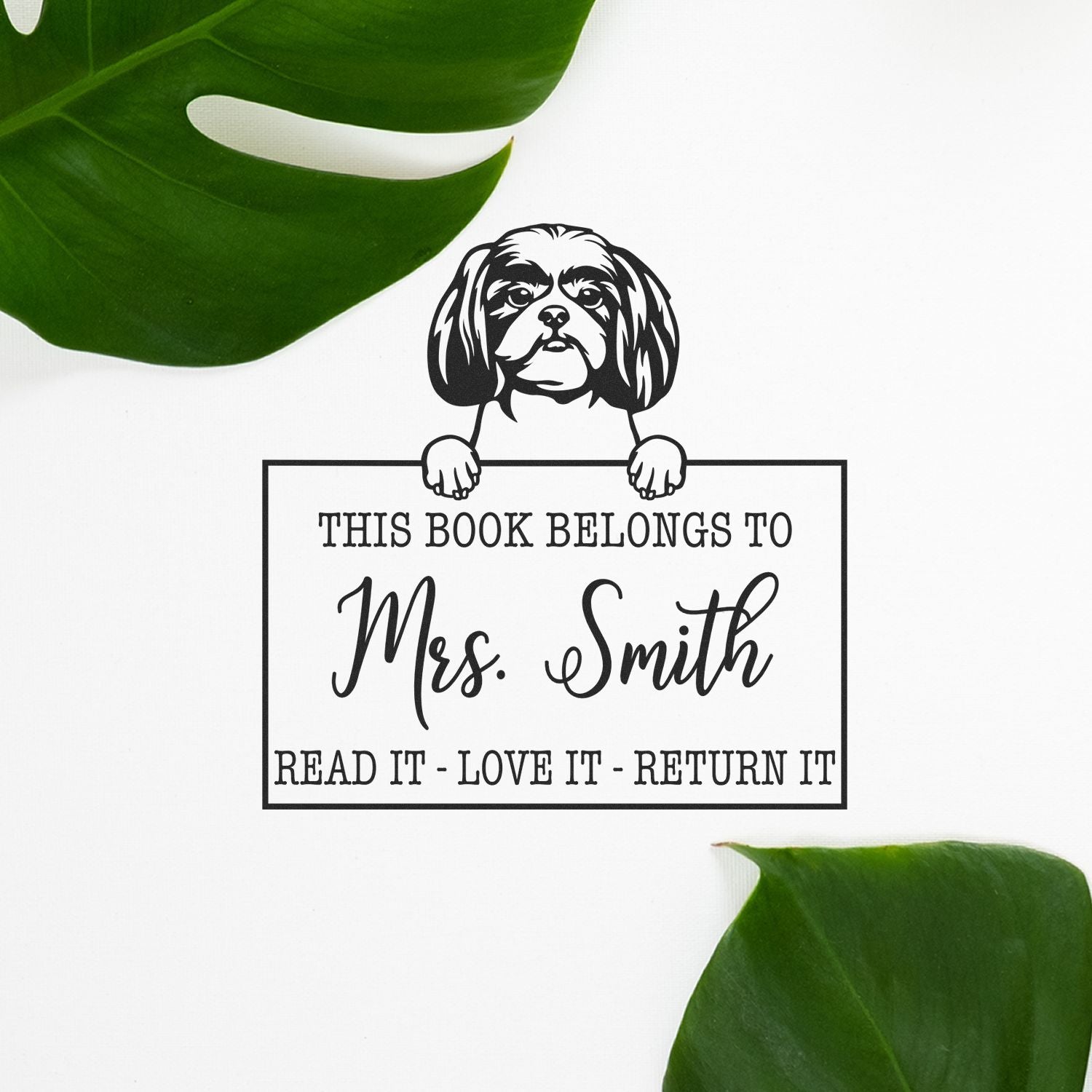 Black custom book stamp and seal with dog illustration, This Book Belongs to Mrs. Smith text, on white with green leaves.
